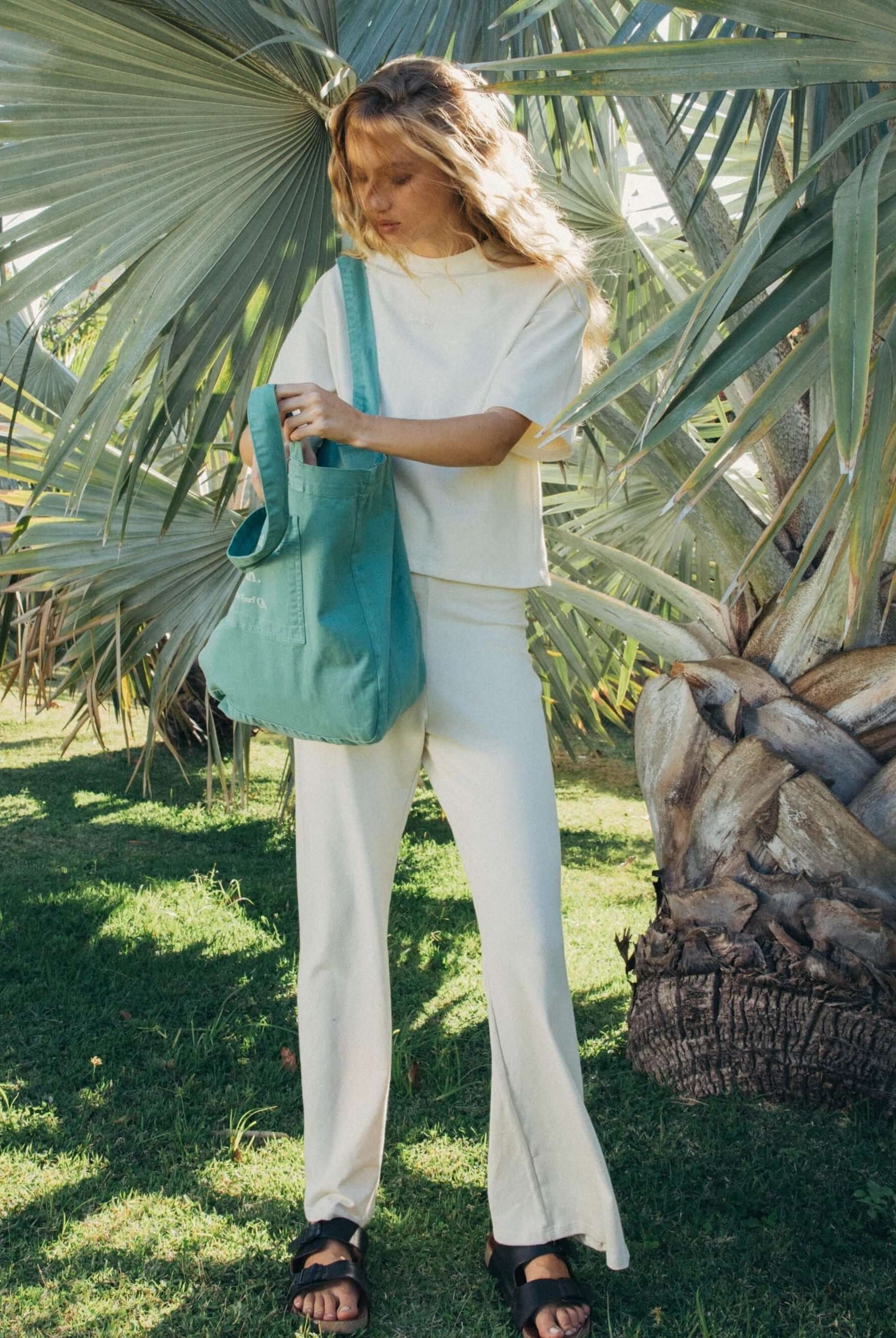 Modelo usando calça bege Gina da Greenish em meio à natureza, destacando estilo e conforto.