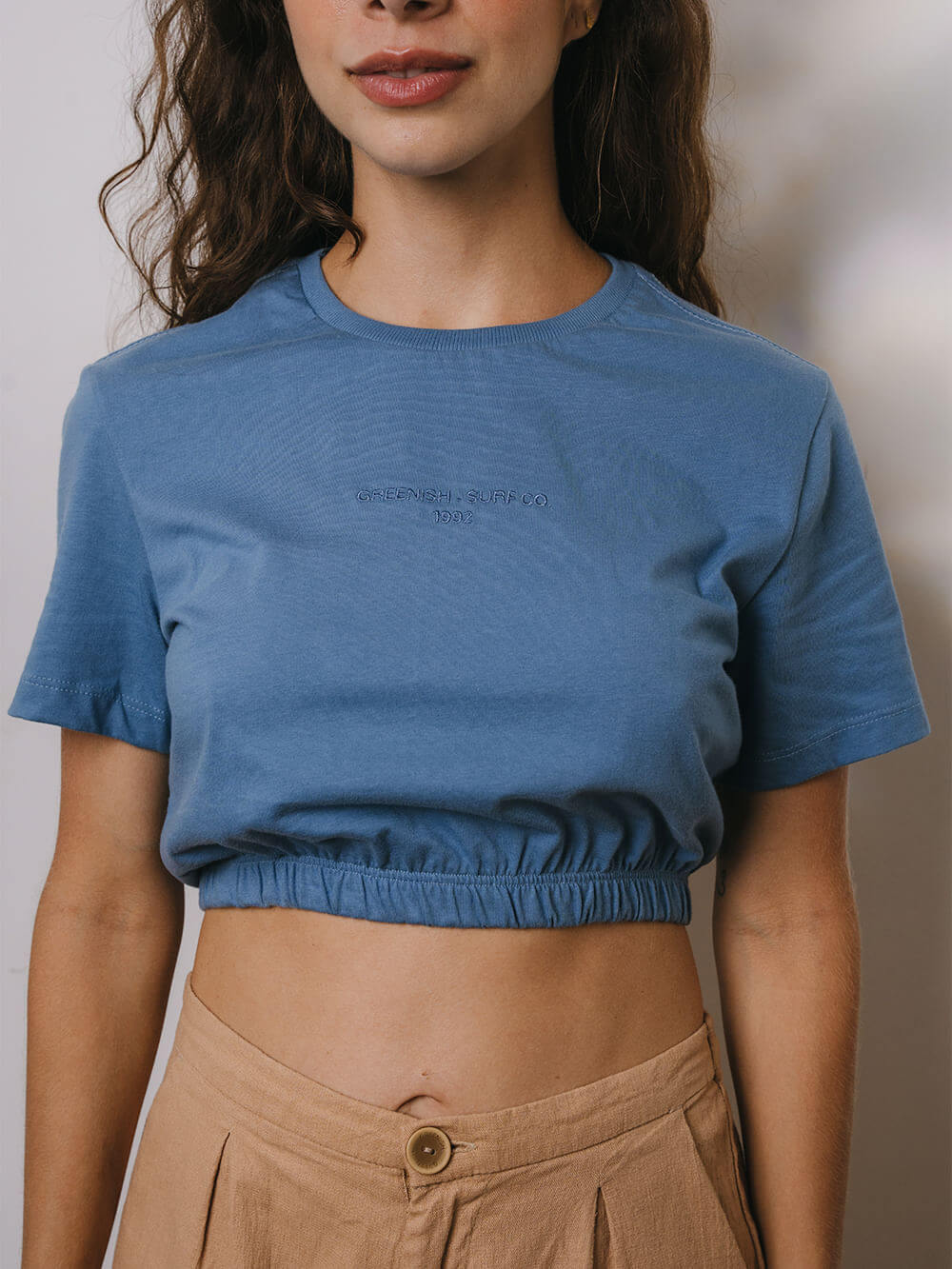 Blusa cropped azul médio da marca Greenish, perfeita para looks casuais e frescos, destacando elegância e conforto.