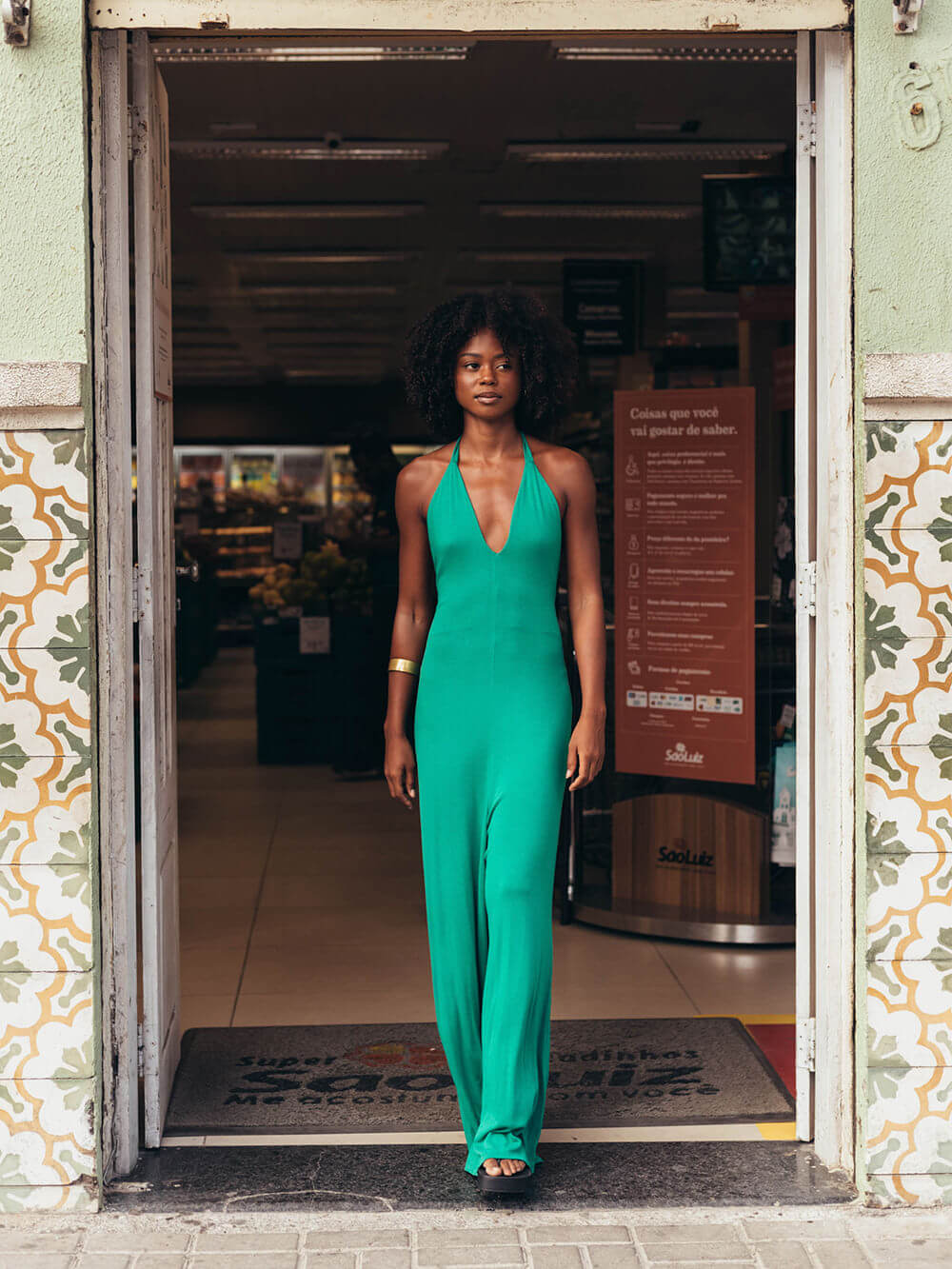 Mulher usando macacão longo verde da Greenish, decote em V e amarração no pescoço, destacando sua personalidade.