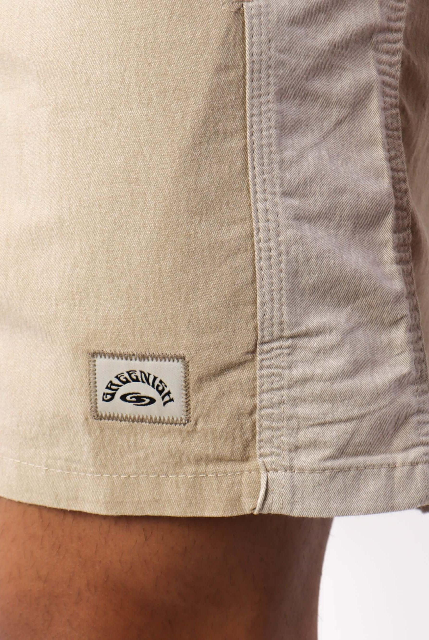 Calça bermuda bege da marca Greenish, destacando o design e o logo exclusivo no tecido.
