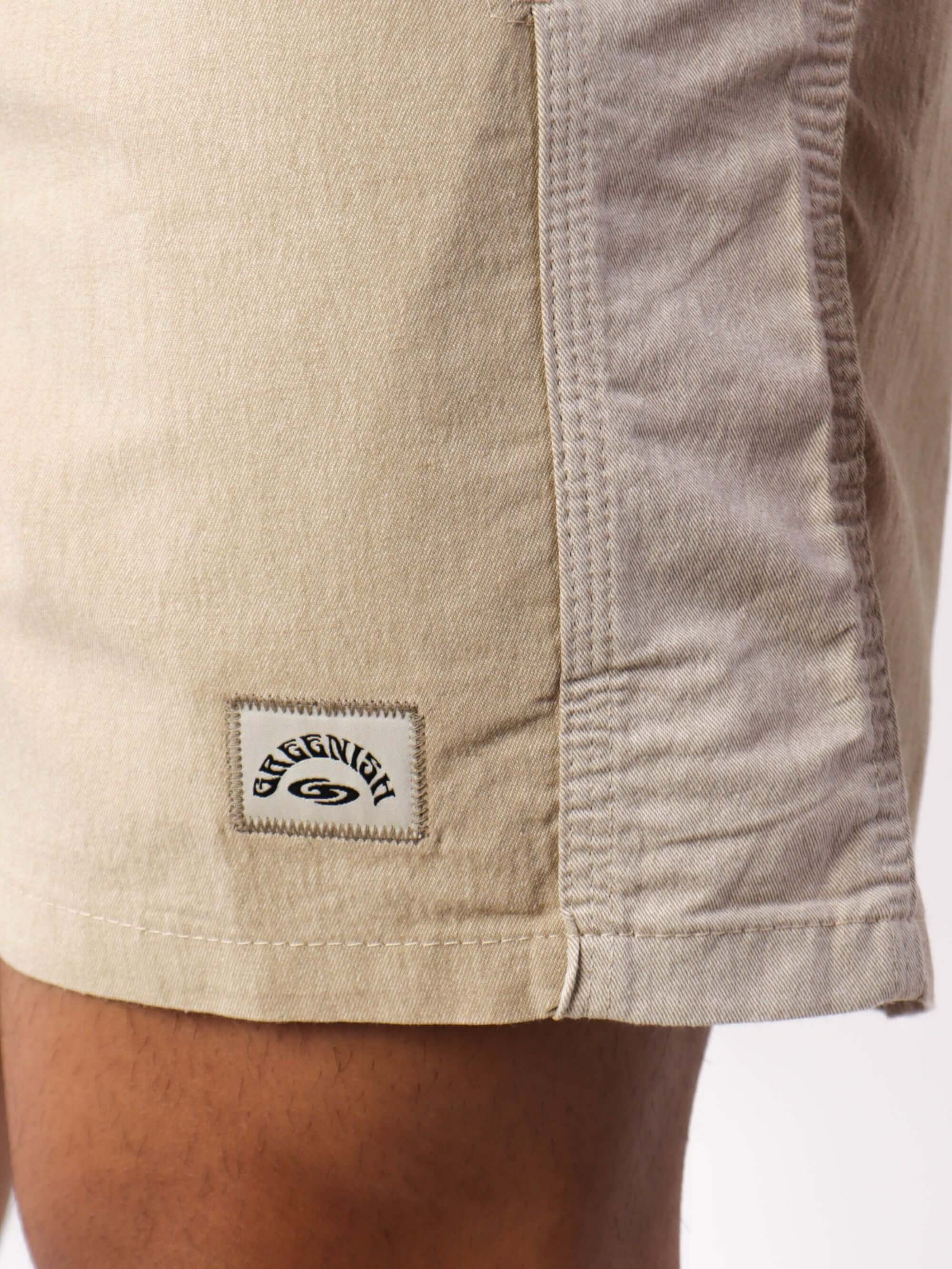 Calça bermuda bege da marca Greenish, destacando o design e o logo exclusivo no tecido.