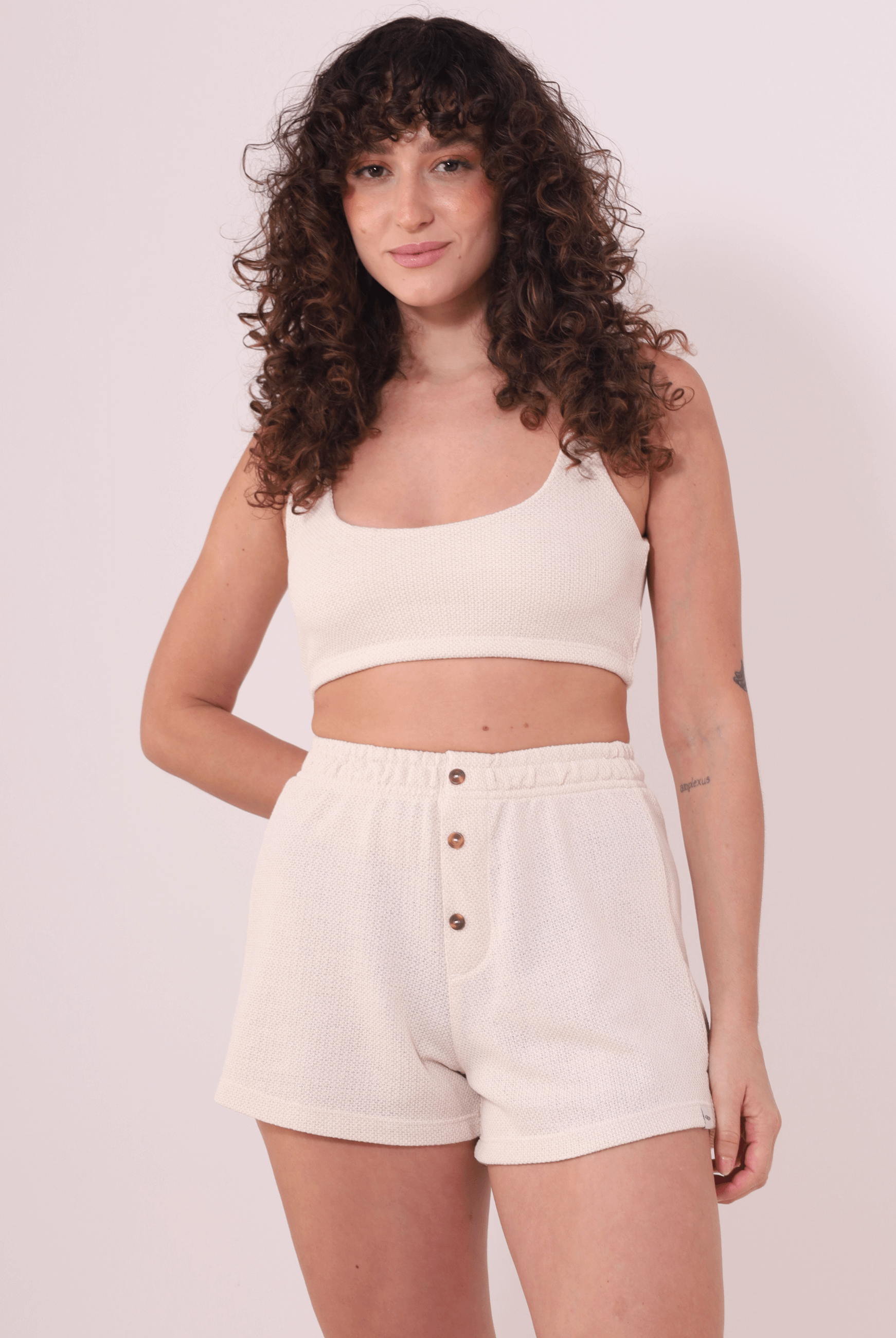 Mulher vestindo Top Nalu Bege da marca Greenish, com decote quadrado, em ambiente neutro. Moda confortável e essencial para o dia a dia.