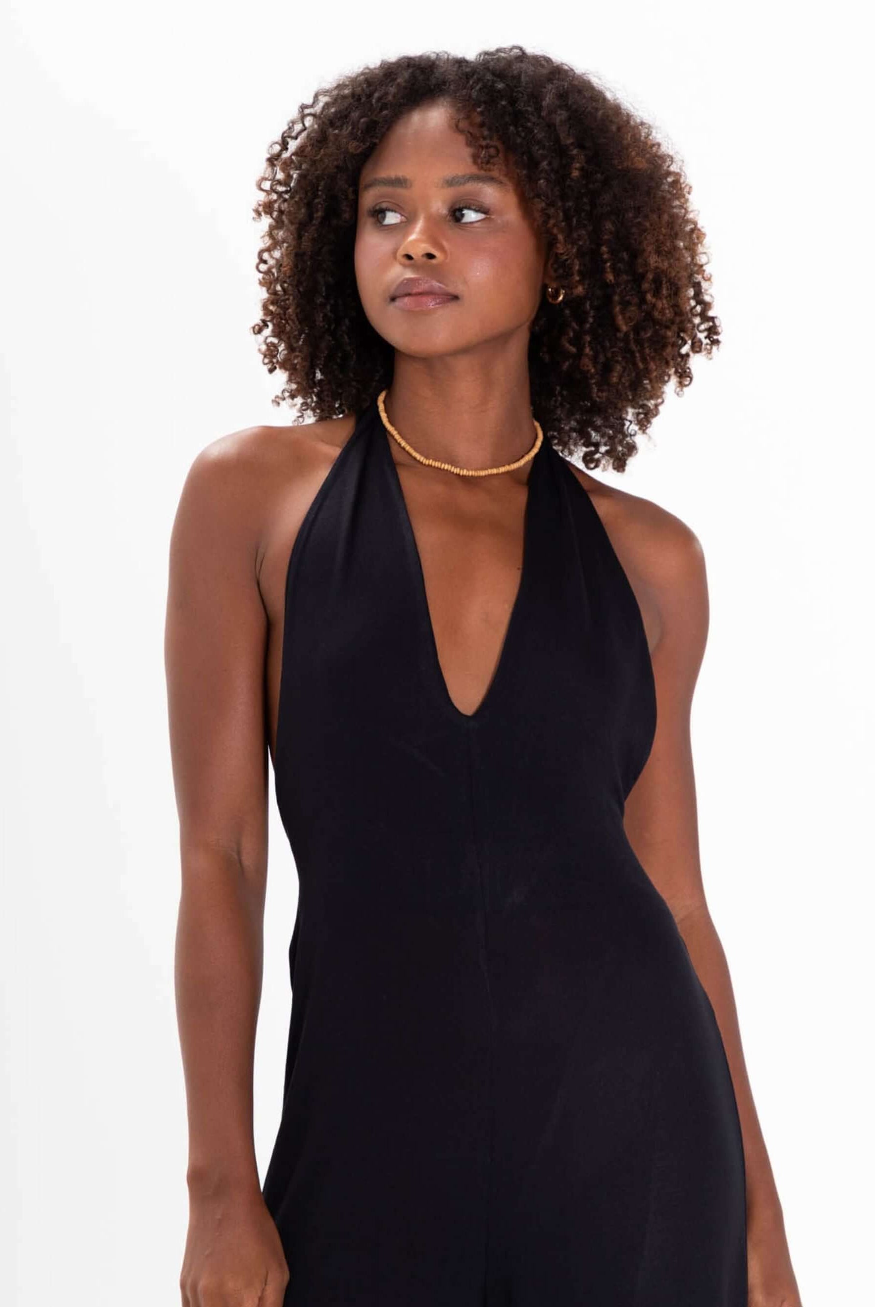 Modelo usando o Macacão Bettah Preto da Greenish, com decote em V e amarração no pescoço, destacando elegância e estilo.