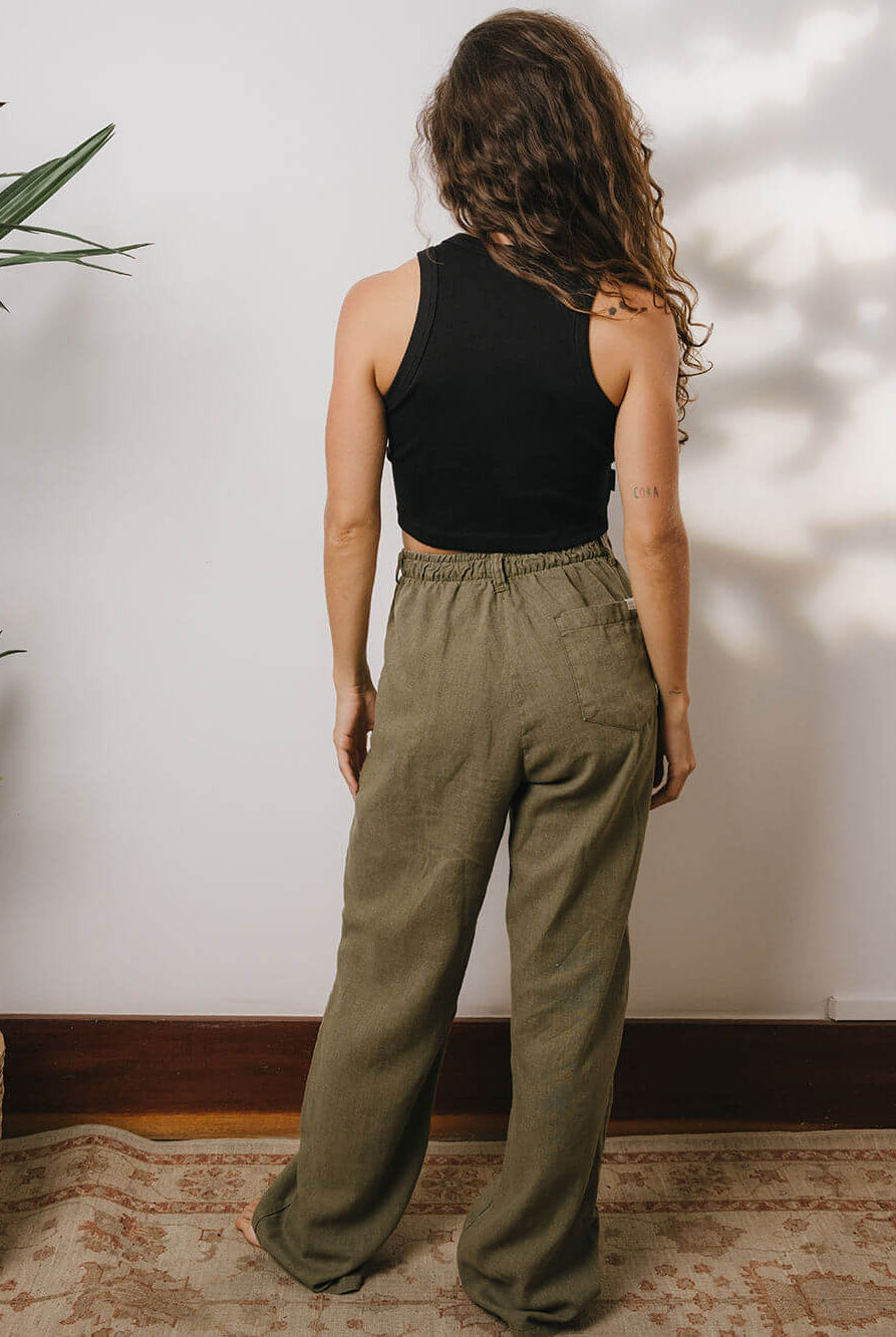 Mulher usando calça linho verde Khay da marca Greenish, vista de costas, perfeita para looks casuais.