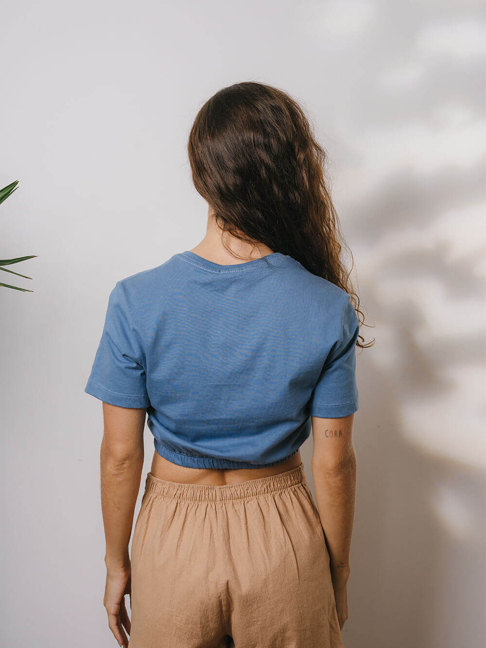 Blusa Sally azul médio da Greenish vista de trás em modelo com calça clara.