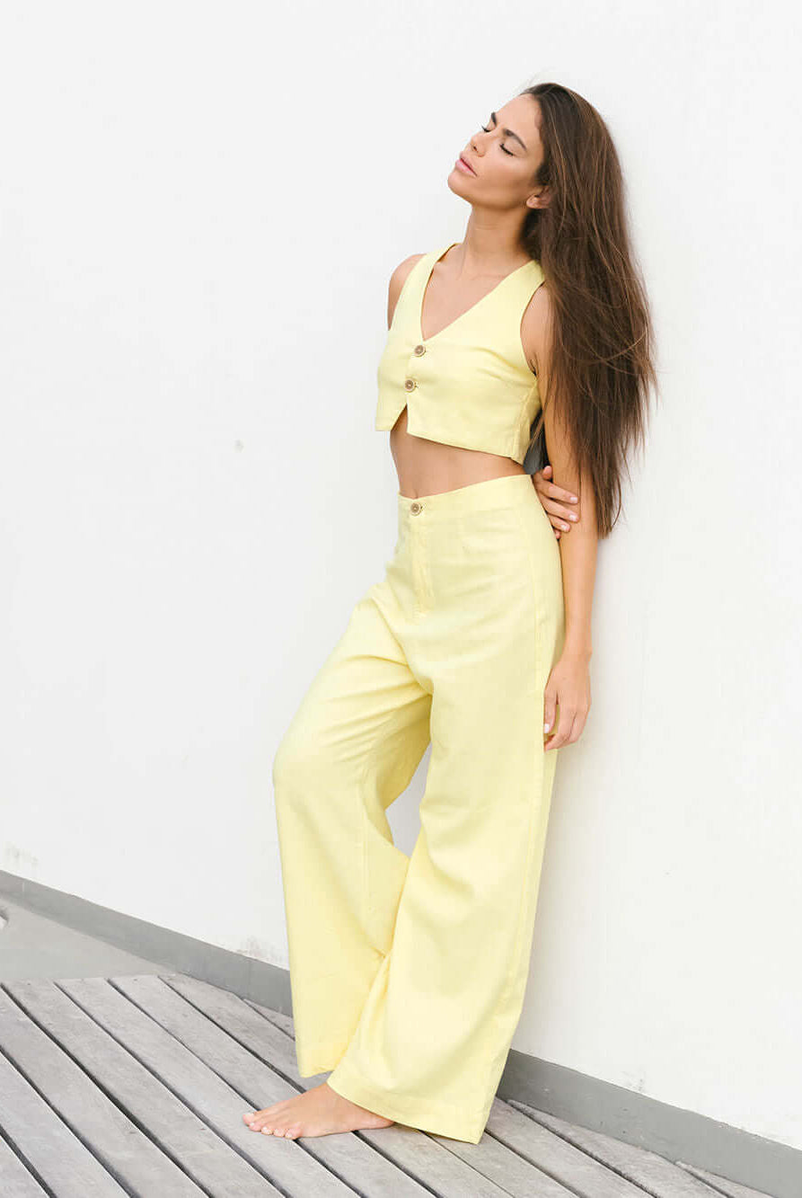 Modelo usando calça Hazel amarela da Greenish, com caimento pantalona e estilo vintage.