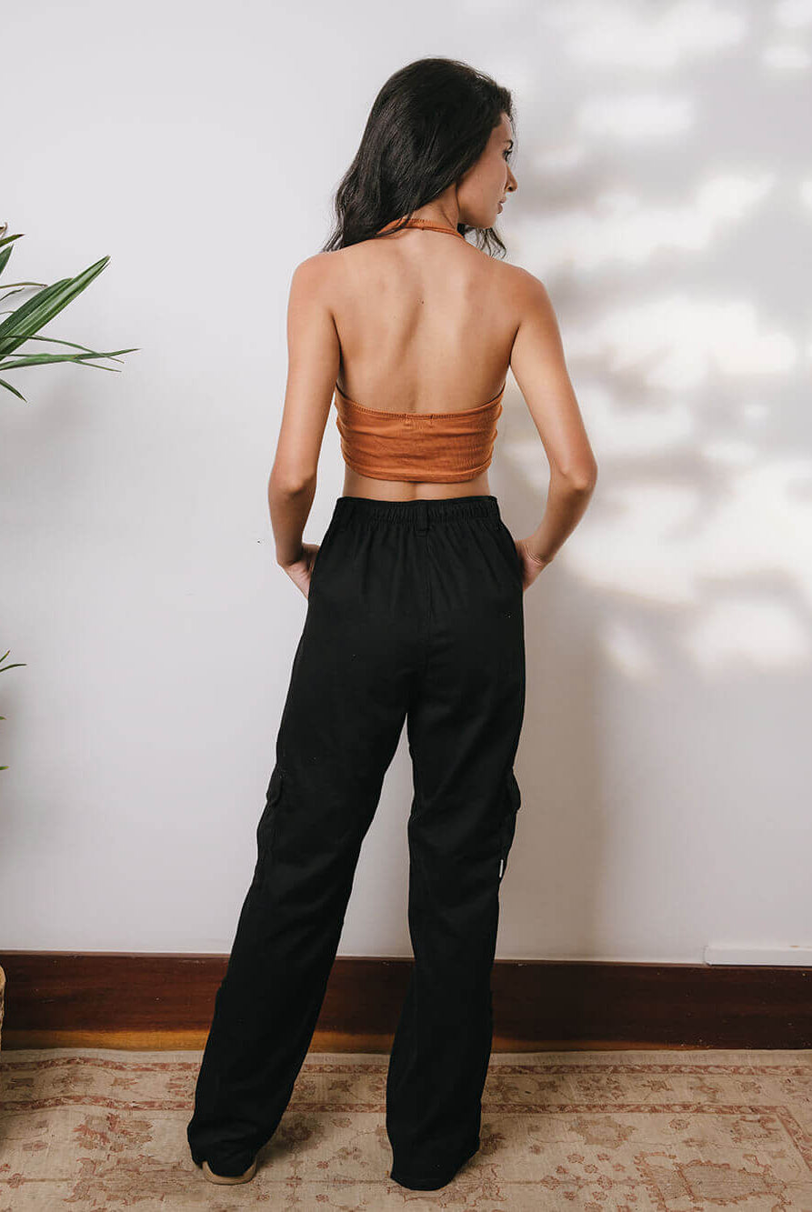 Model usando calça cargo sarja Gio preta, vista de costas, com top cropped. Estilo moderno e confortável da Greenish.