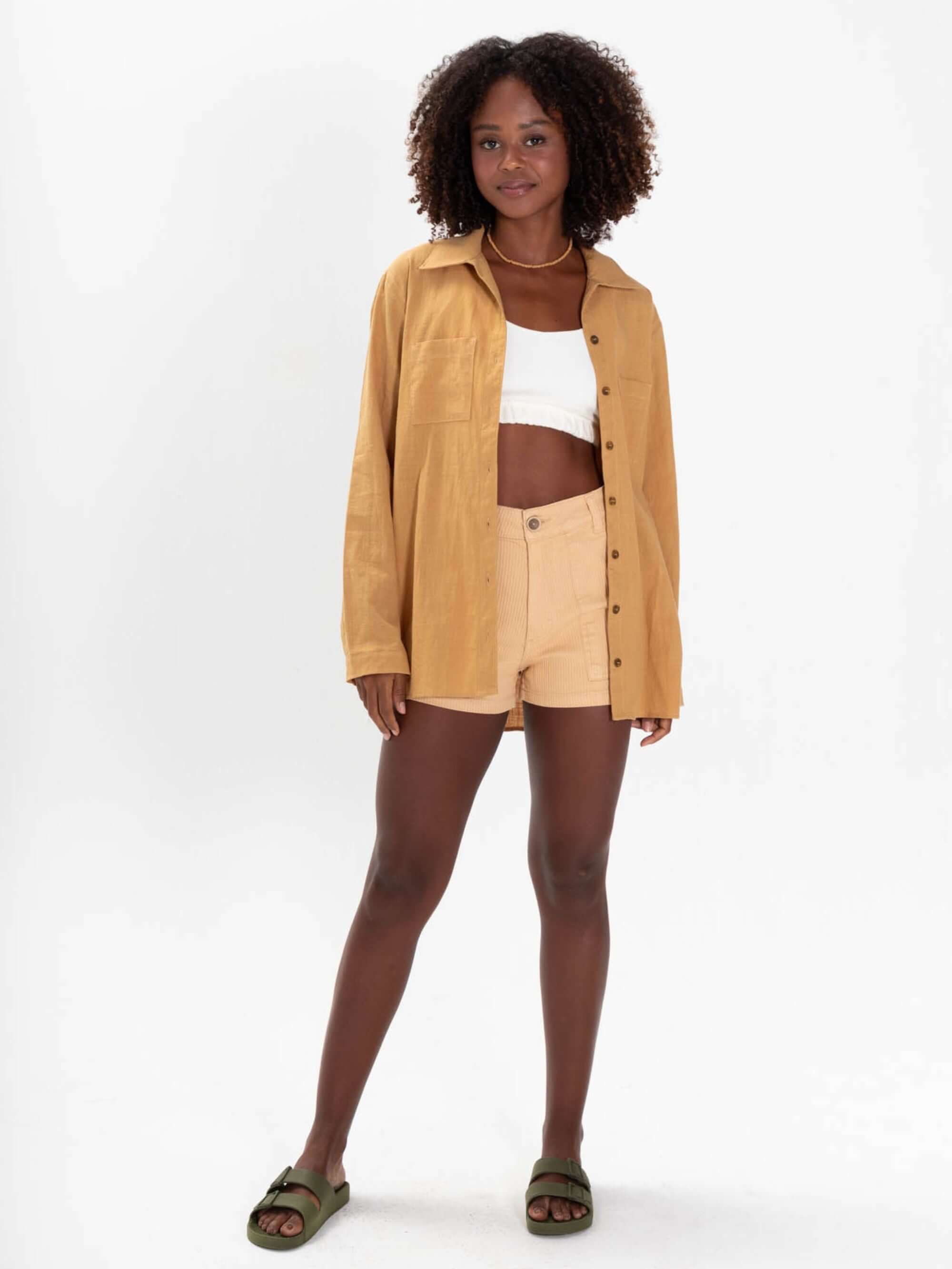 Modelo usando a Camisa Jennie verde da marca Greenish, combinando com shorts claros e top branco.