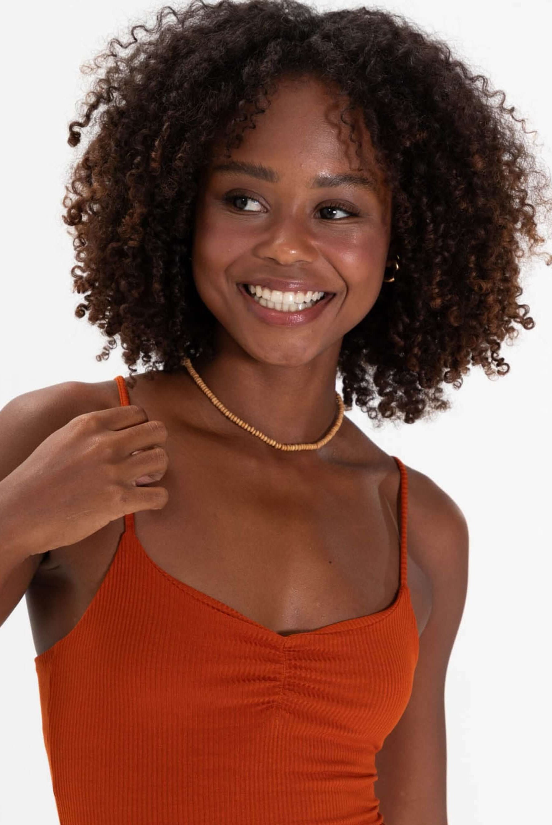 Modelo sorrindo com vestido curto telha da marca Greenish, destacando estilo e conforto.