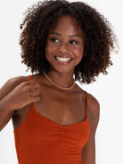 Modelo sorrindo com vestido curto telha da marca Greenish, destacando estilo e conforto.