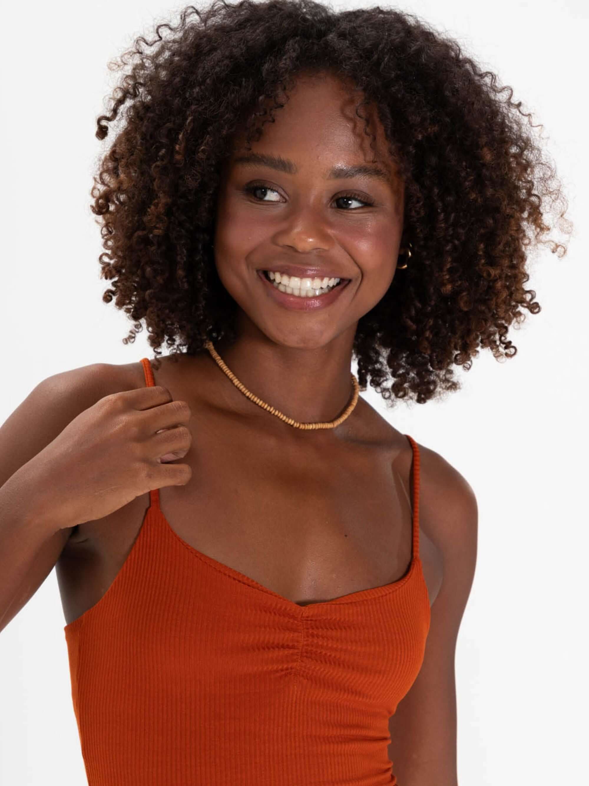 Modelo sorrindo com vestido curto telha da marca Greenish, destacando estilo e conforto.