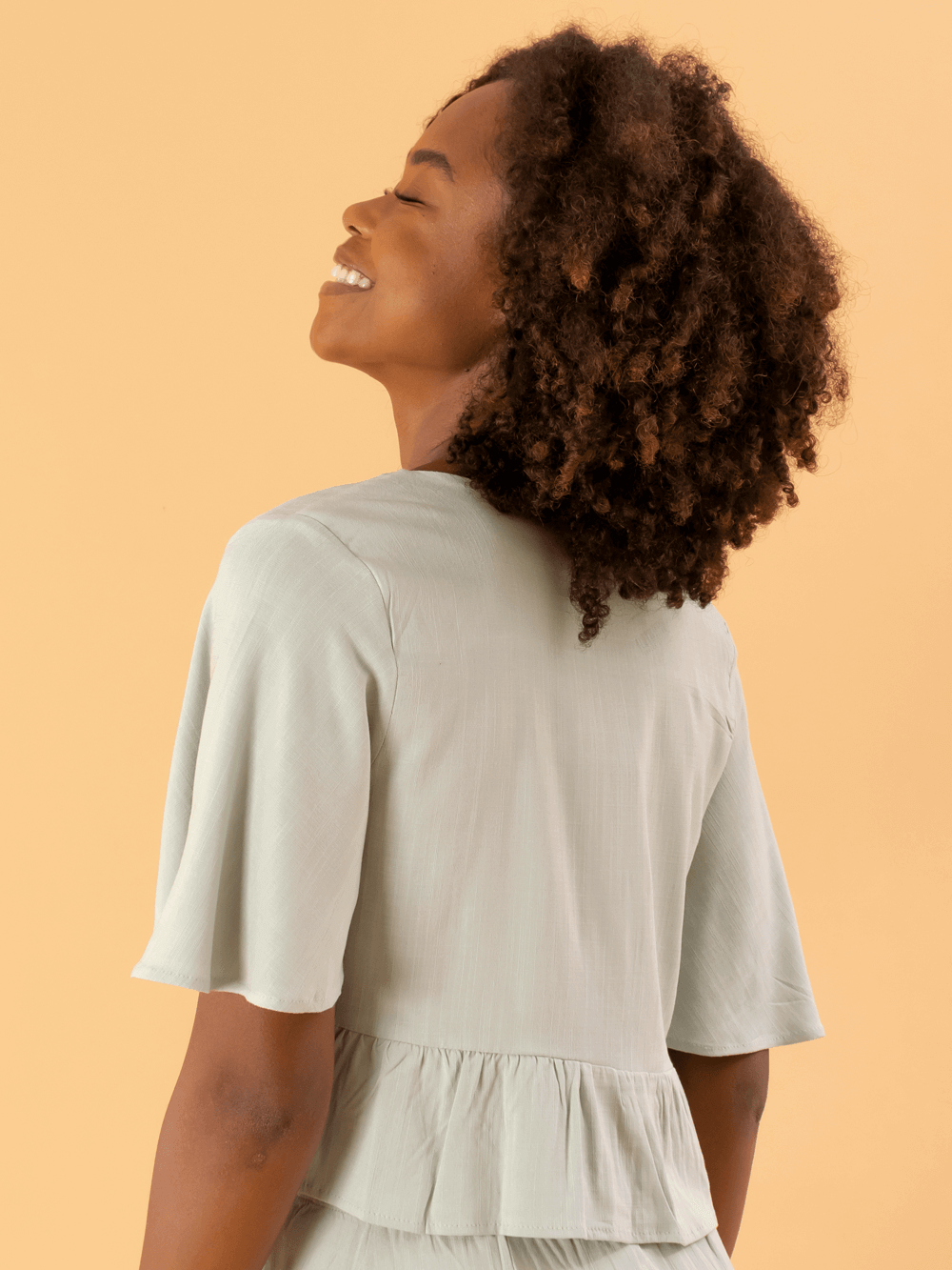 Blusa Kali verde da marca Greenish, com mangas bufantes e detalhe de babado nas costas.