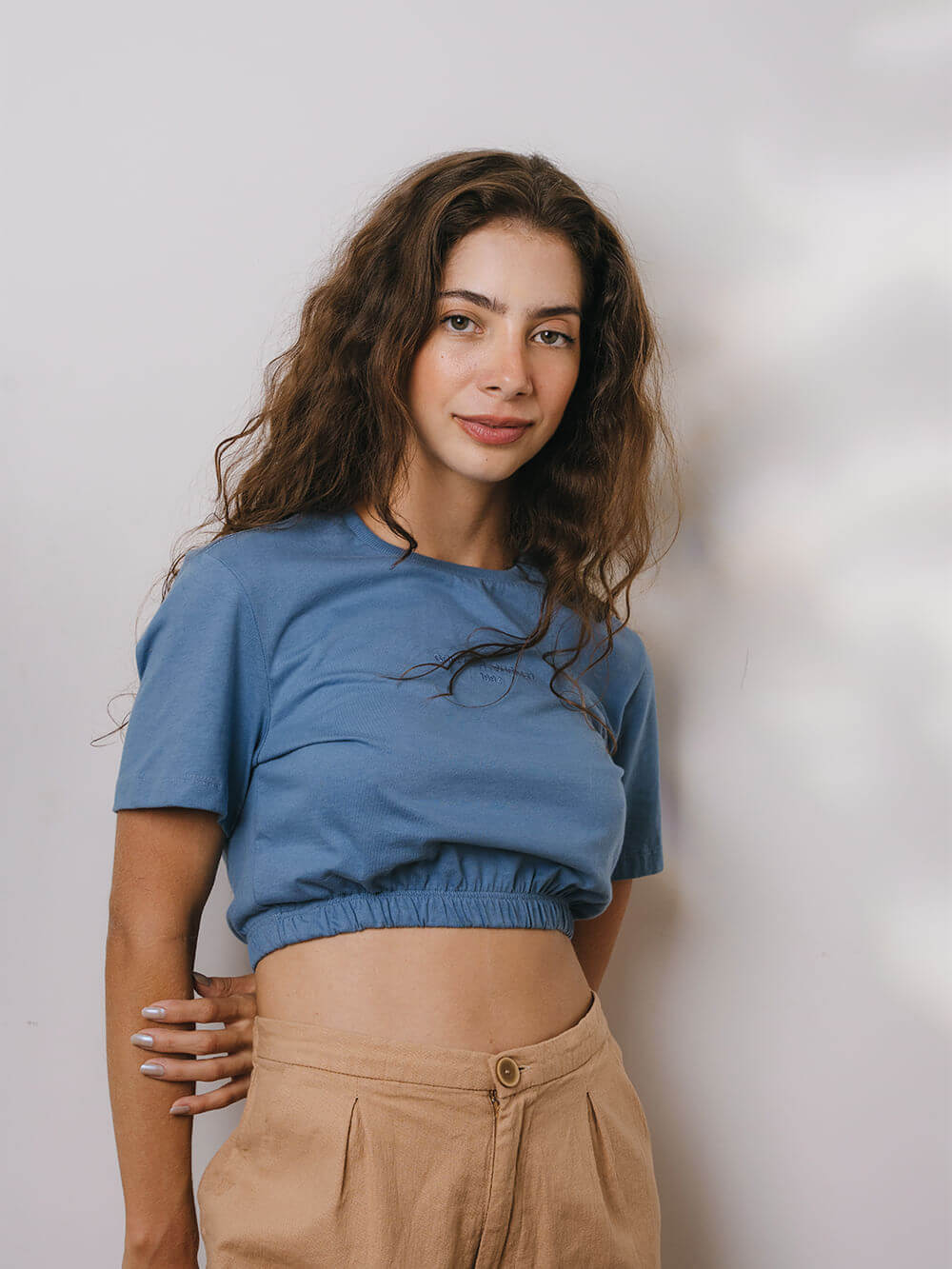 Modelo vestindo blusa Sally azul médio da marca Greenish, com detalhe franzido na cintura.