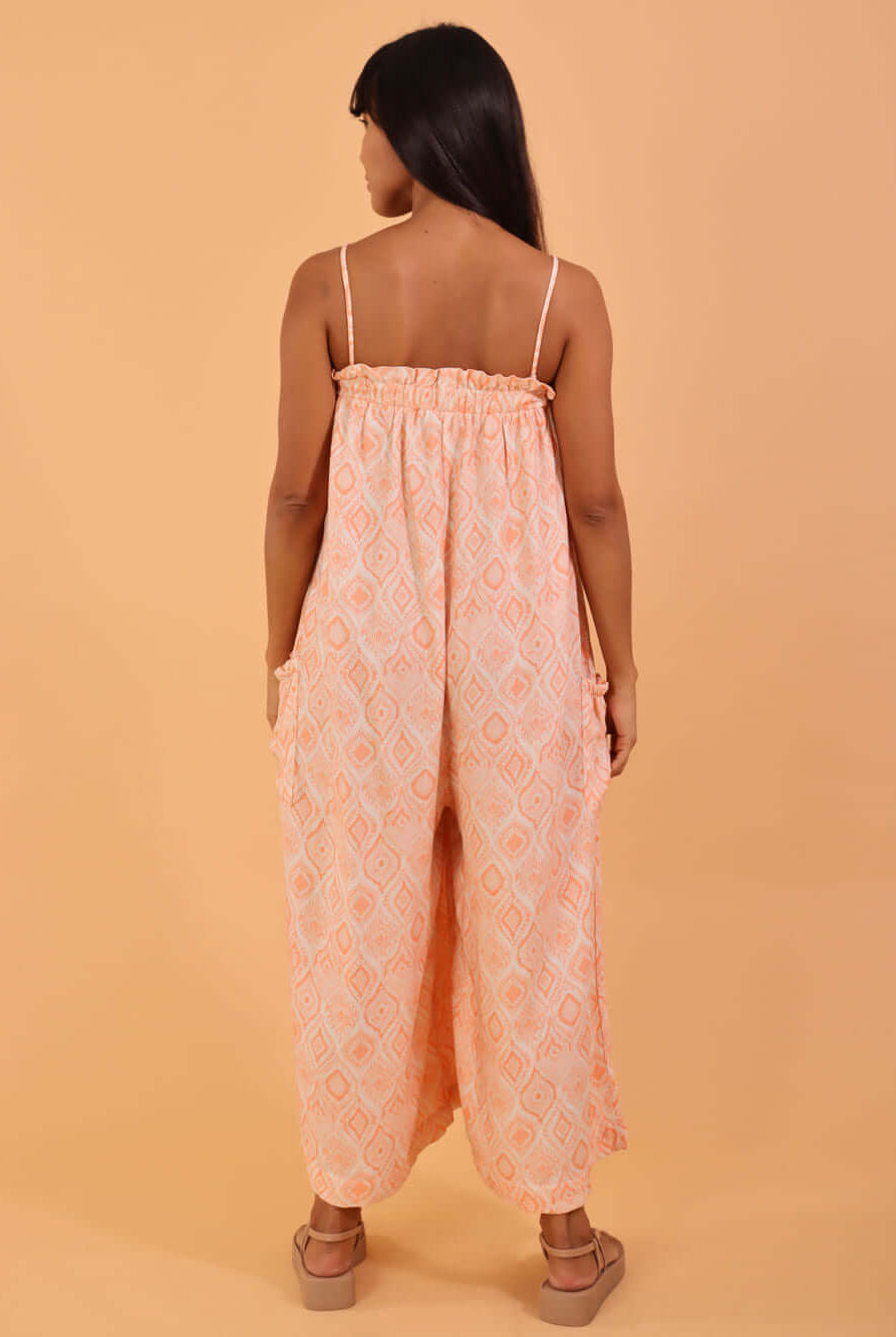 Macacão midi Emily da Greenish na cor coral, sendo exibido de costas em fundo laranja.