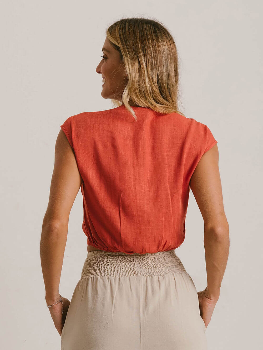 Blusa Ruth da Greenish, cor laranja, tecido leve, caimento soltinho e sem mangas, vista traseira.