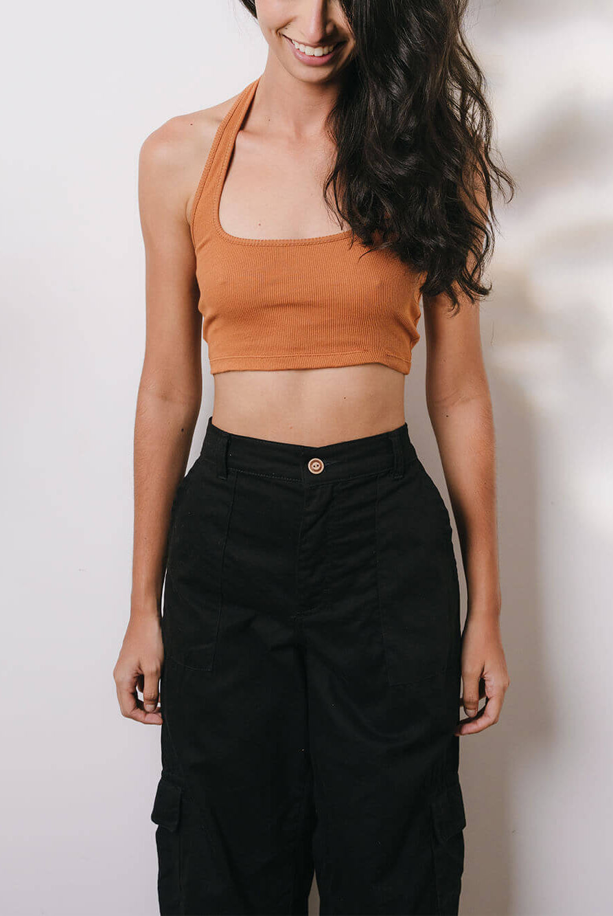 Modelo usando calça cargo sarja preta da Greenish com blusa cropped laranja, estampa casual e moderna.