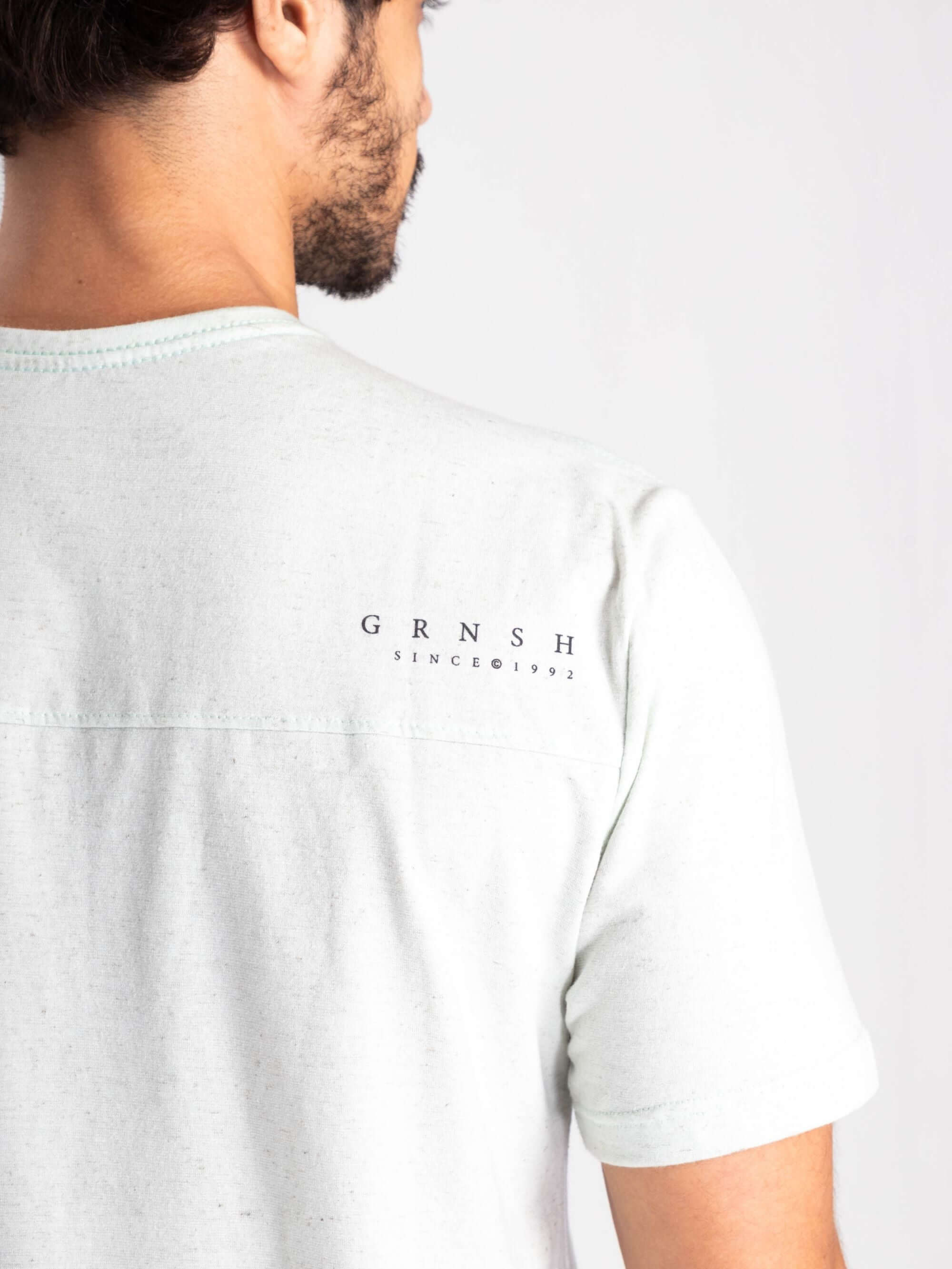 Camiseta Elemental natural da marca Greenish, vista de trás, com logo GRNSH em destaque.