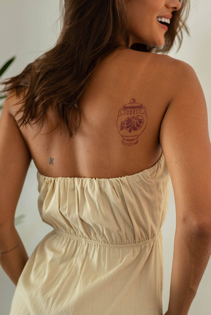 Modelo usando vestido curto bege, com um lindo desenho no ombro, exalando estilo e conforto.