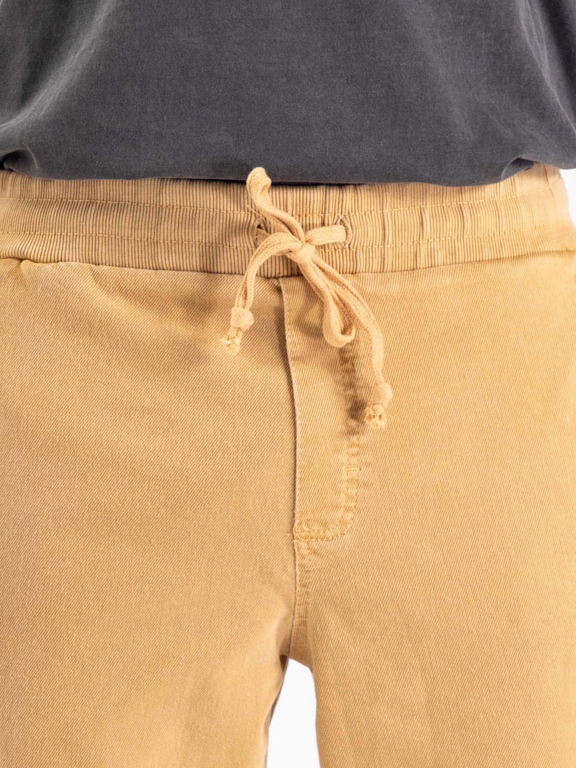 Detalhe da calça Rio Stone - Amarelo da Greenish, com cós elástico e cadarço para ajuste.