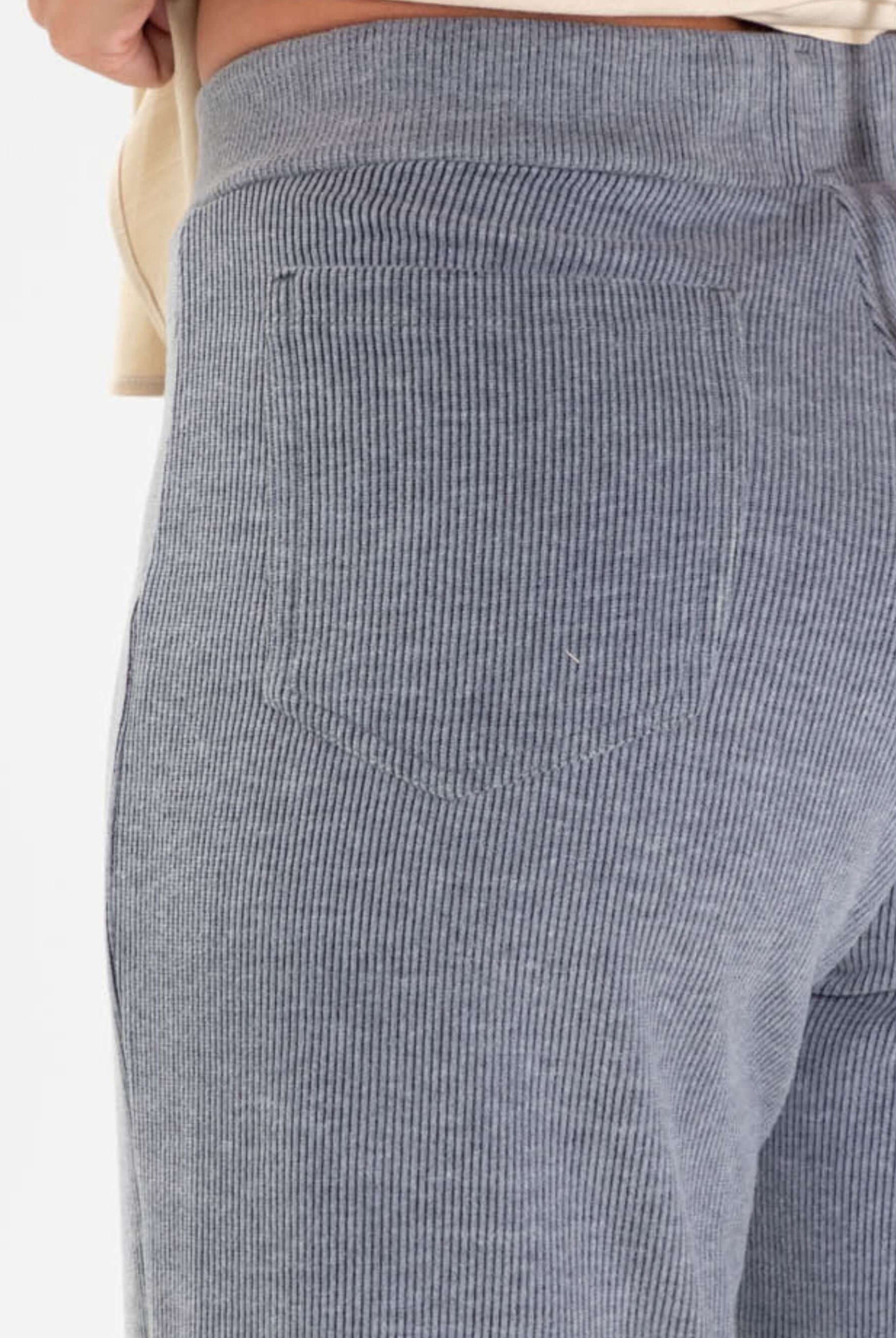 Detalhe do bolso traseiro da calça Heaven da Greenish, em tecido cinza listrado, combinando conforto e estilo.