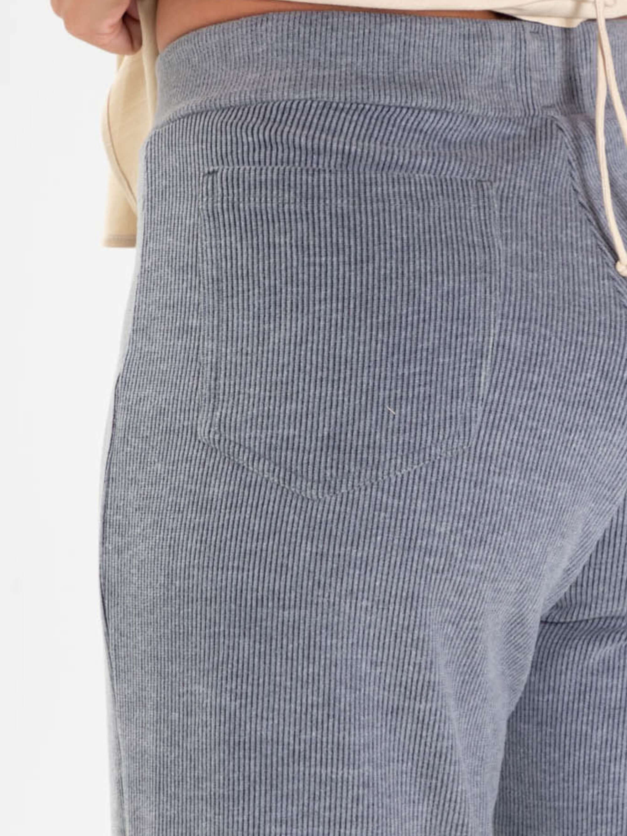 Detalhe do bolso traseiro da calça Heaven da Greenish, em tecido cinza listrado, combinando conforto e estilo.