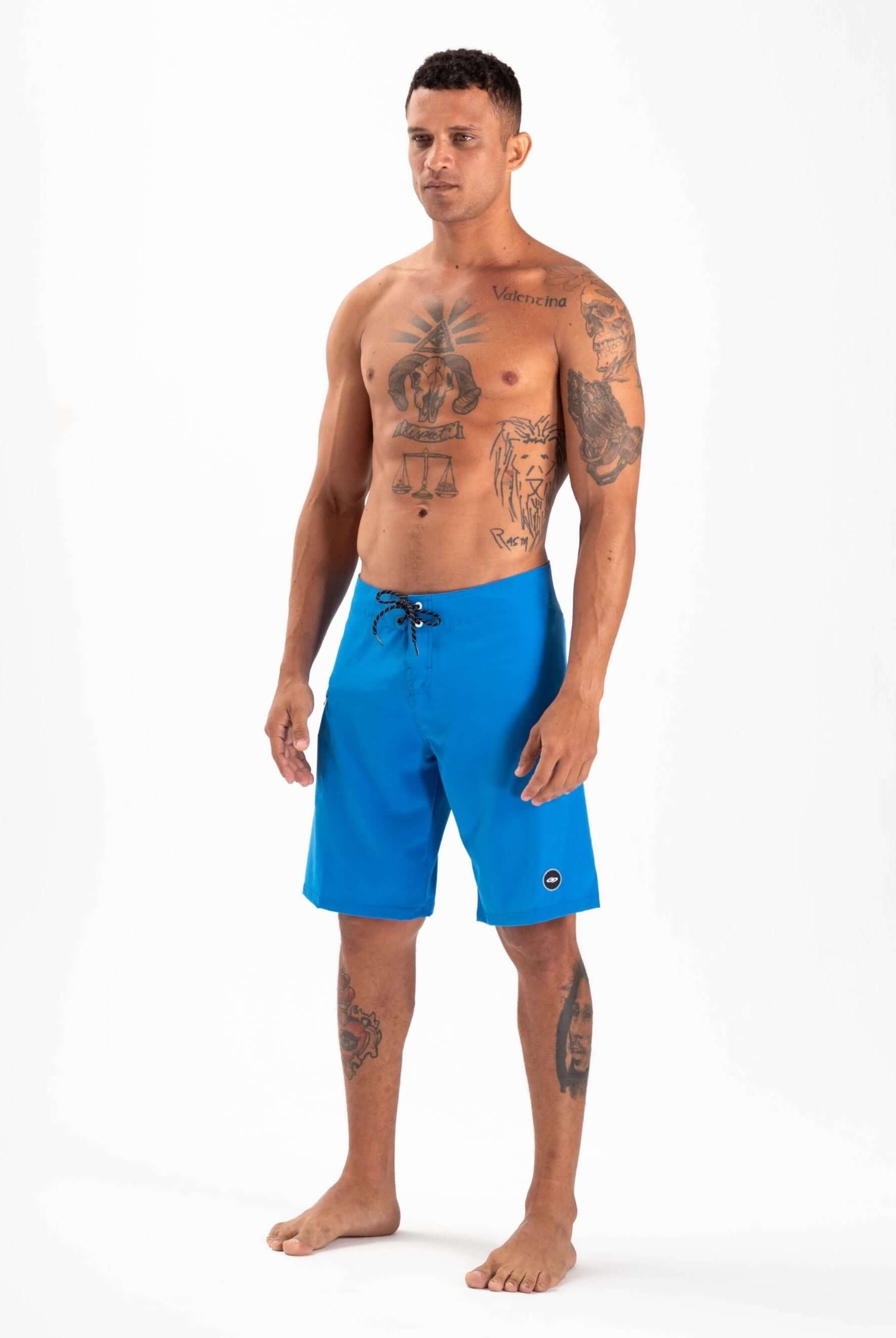 Model wearing Greenish Total Stretch Boardshorts in blue, ideal for high-performance water sports.