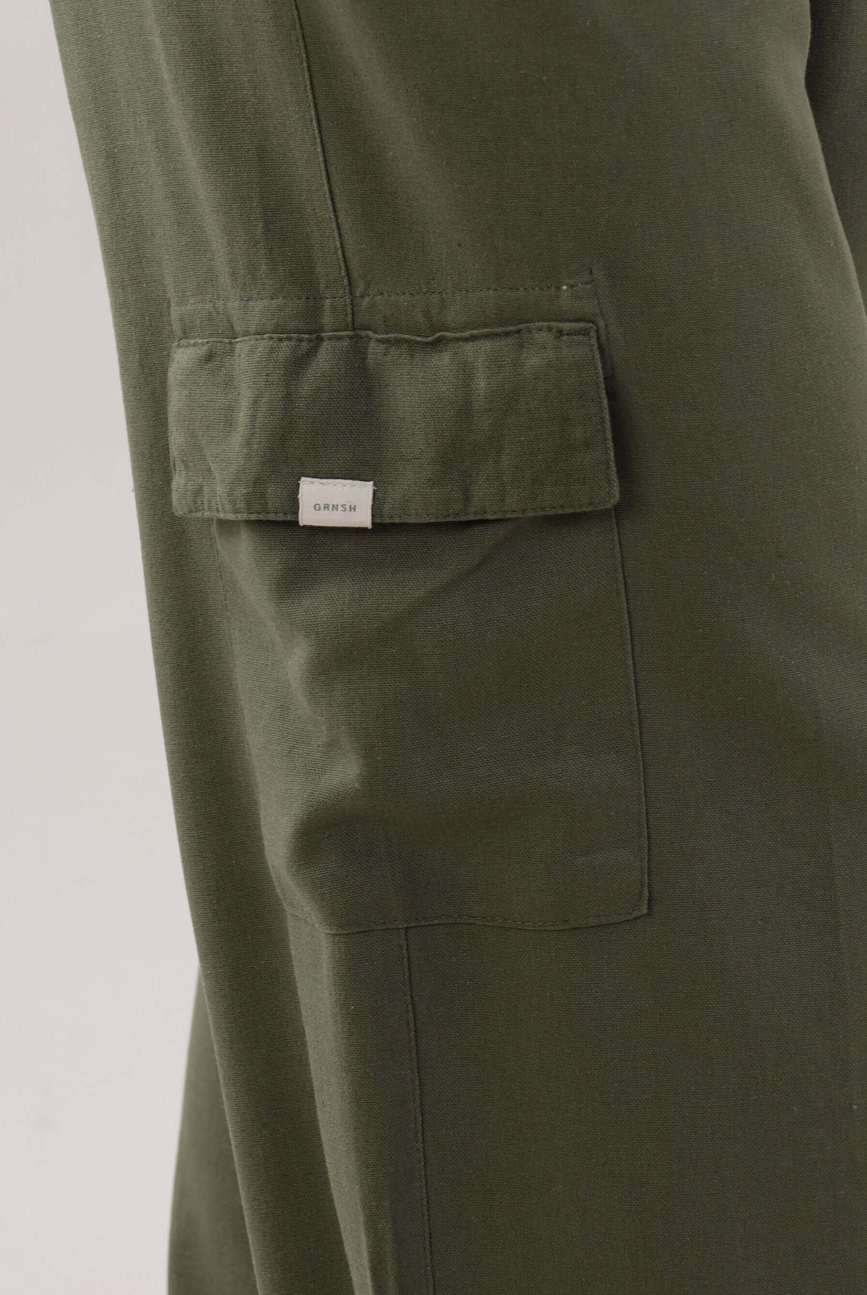 Calça reta cargo Taia da Greenish na cor verde escuro, com detalhe do bolso lateral.