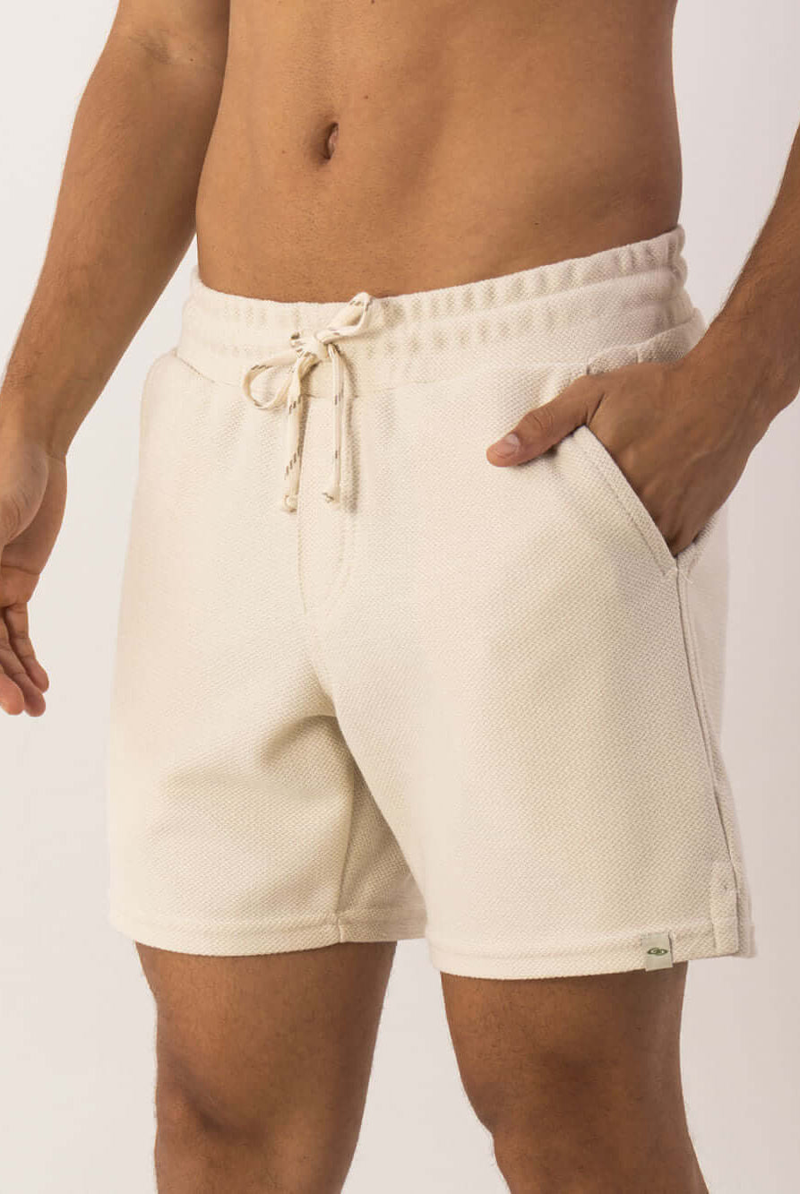 Bermuda Moletom Alpes Off White Greenish, modelagem vintage, com bolso e cós elástico para conforto e estilo.