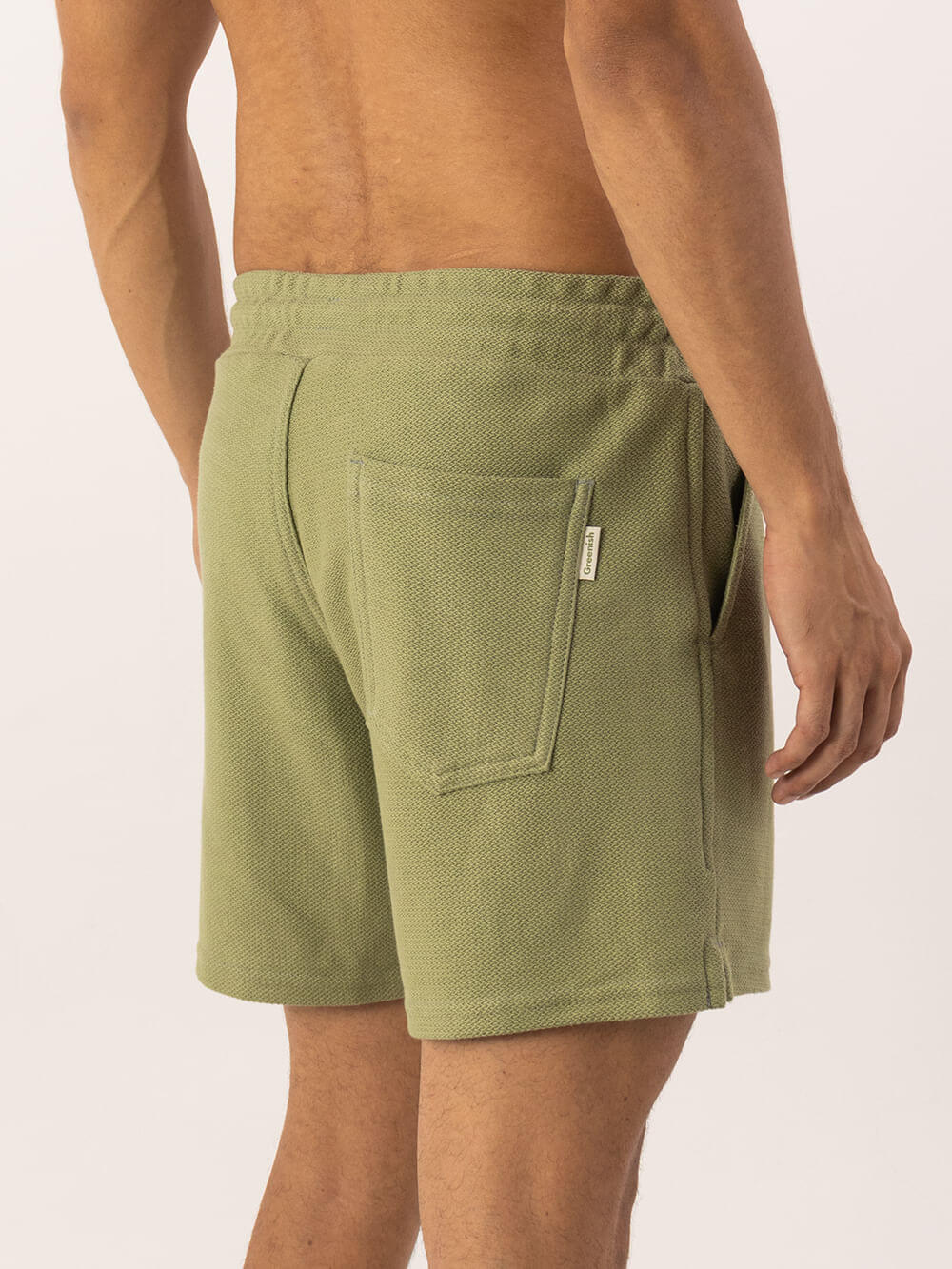 Bermuda Moletom Alpes Verde Greenish com bolso traseiro e detalhe de cadarço, modelagem vintage e confortável.