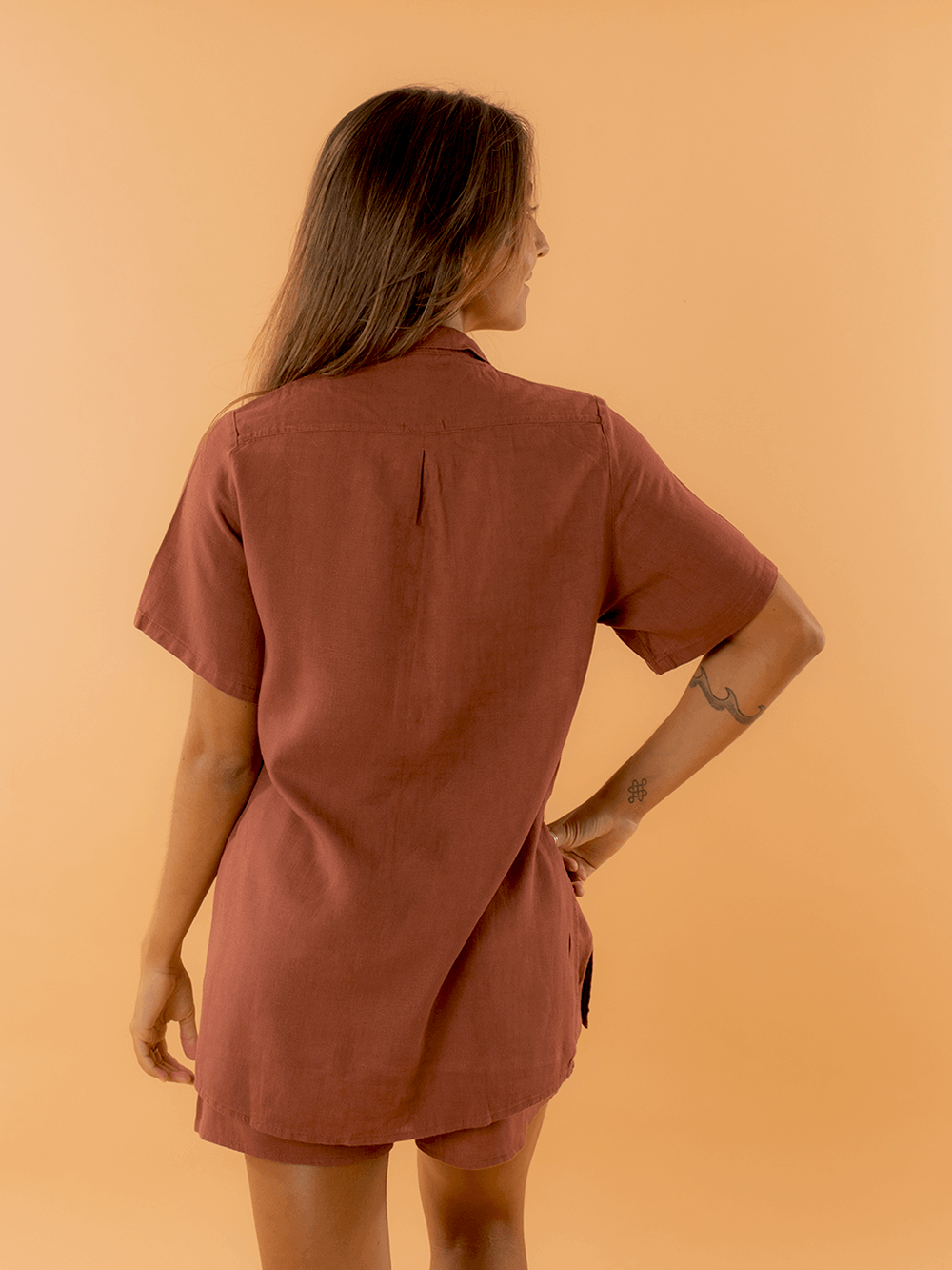 Modelo usando a camisa Tayla marrom da marca Greenish, vista de costas, destacando seu estilo moderno.