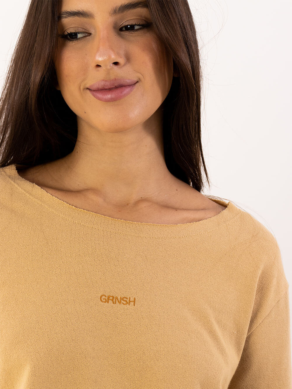 Modelo usando camiseta verde caqui da marca Greenish, com logo em destaque, estilo cropped e descontraído.