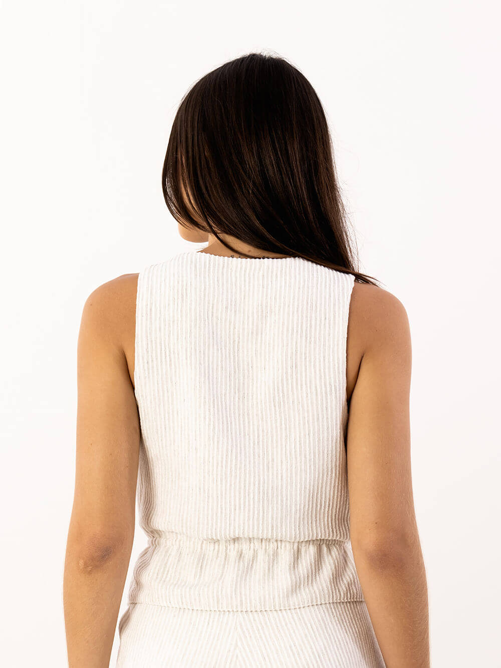 Mulher com blusa Tiemi da Greenish, vista de costas, destacando o design sofisticado e confortável em malha bege.