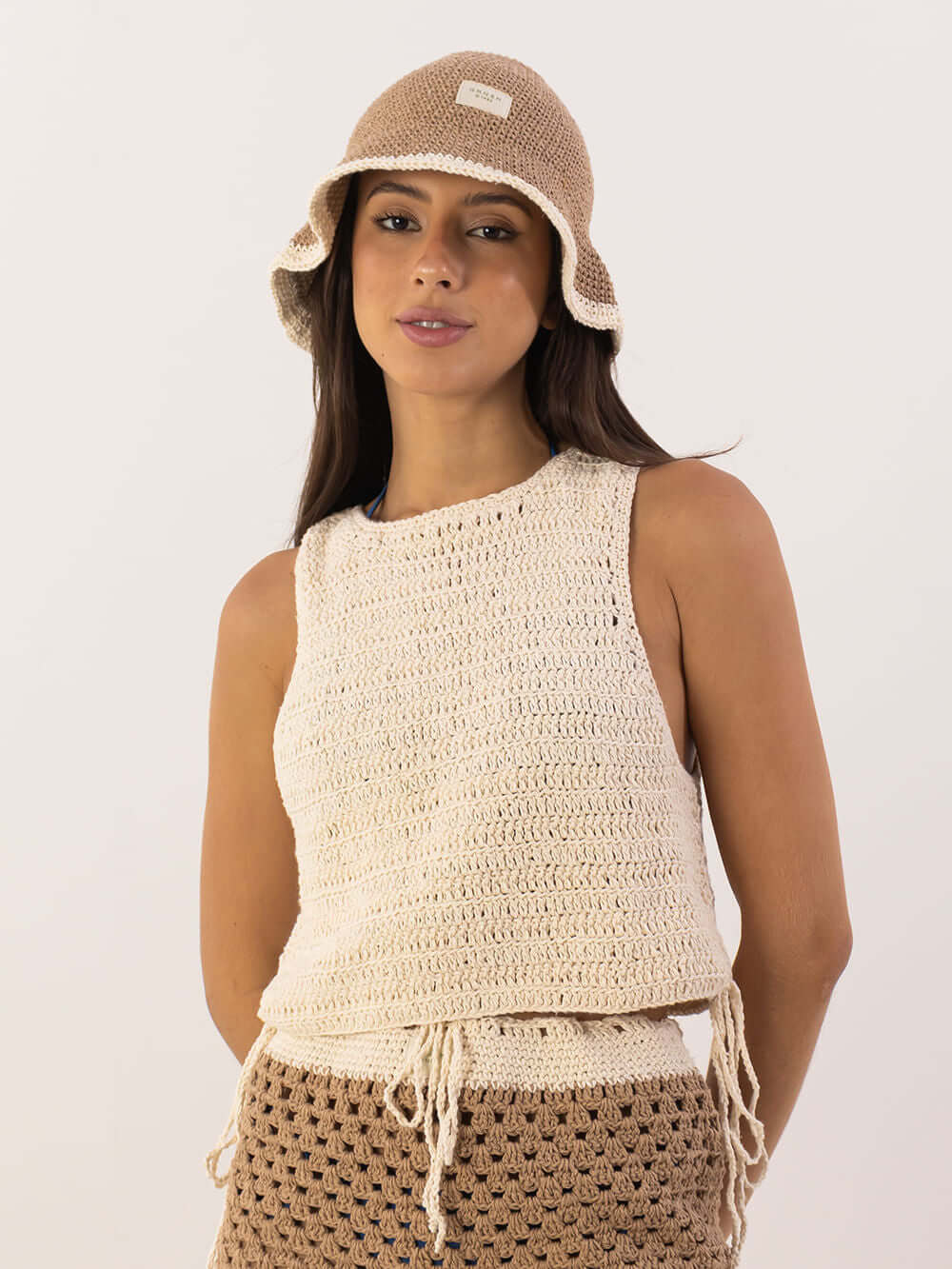 Modelo usando a Blusa Tropical da Greenish em crochê, com chapéu de palha em tom neutro.