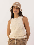 Modelo usando a Blusa Tropical da Greenish em crochê, com chapéu de palha em tom neutro.