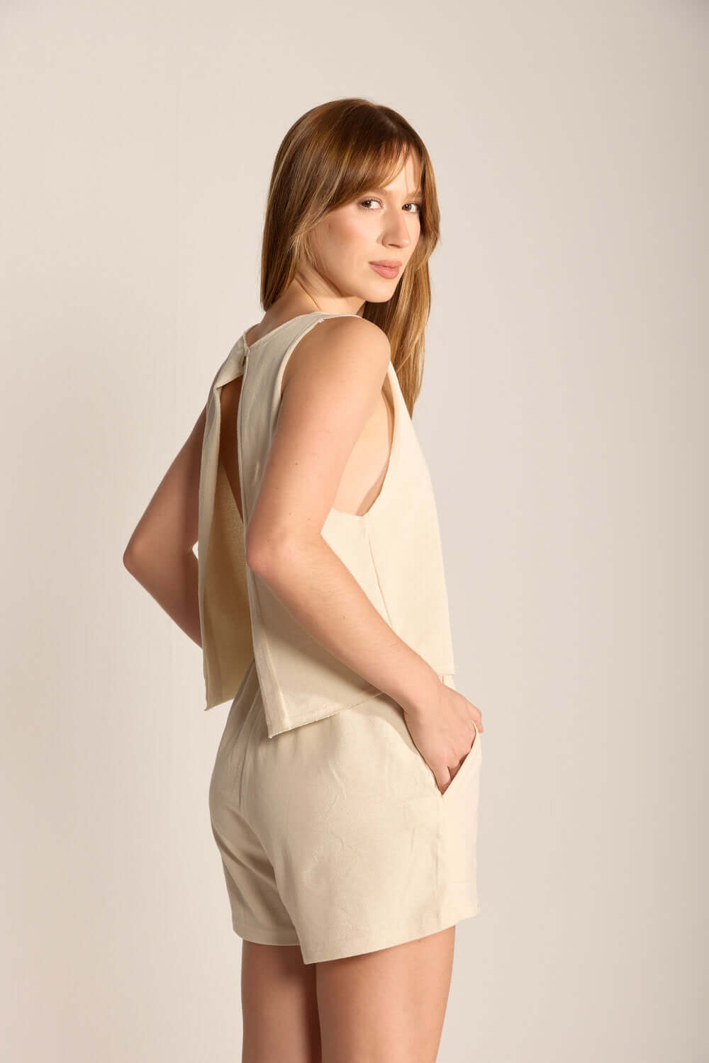 Modelo usando blusa Gina bege da marca Greenish, destacando o corte moderno e a combinação com shorts.