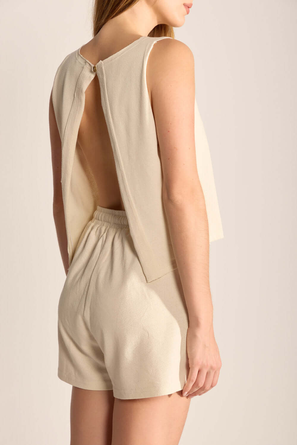 Look da blusa Gina em bege nas costas, combinada com shorts, ideal para estilo e conforto. Marca Greenish.