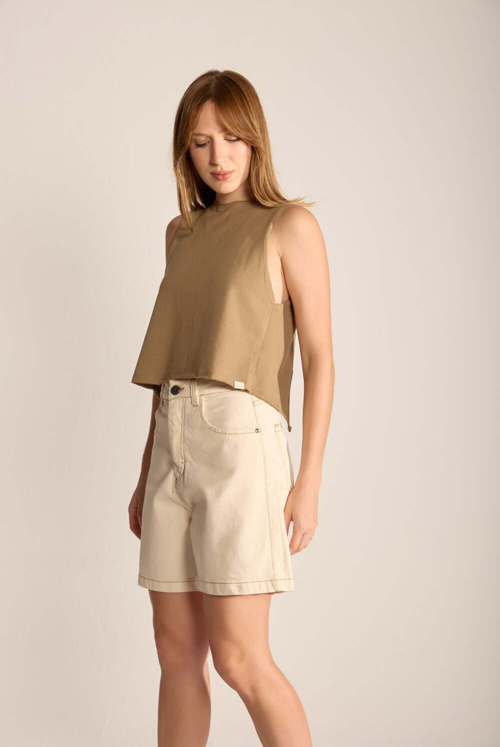 Modelo usando blusa verde musgo da Greenish com shorts, mostrando estilo casual e conforto.