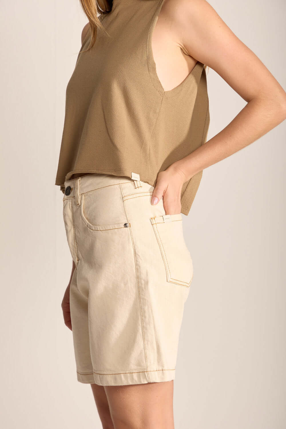 Modelo usando blusa bege e shorts claros da Greenish, destacando conforto e estilo para ocasiões diversas.