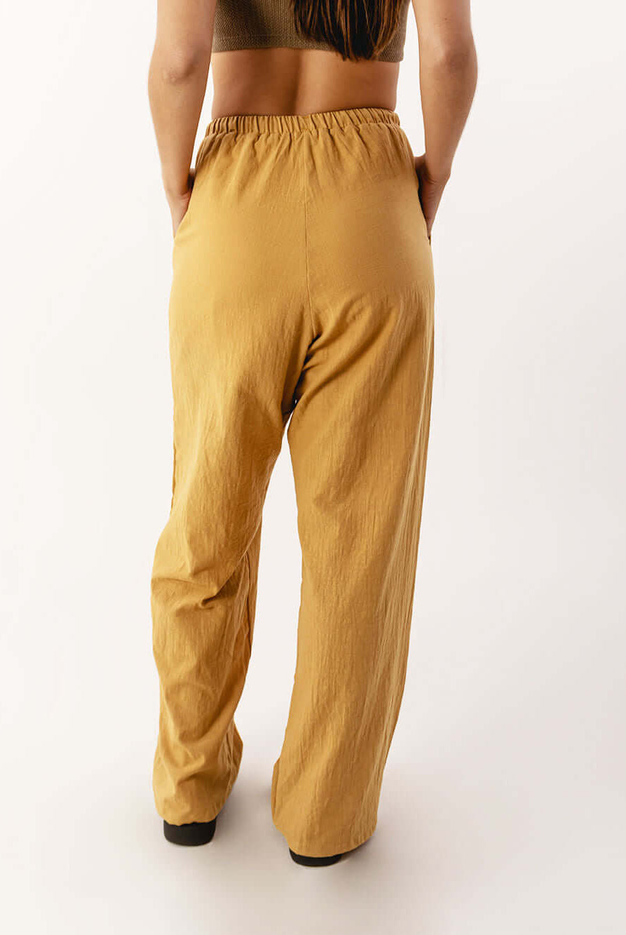 Calça Nat da Greenish em caqui, vista traseira com cós elástico e caimento solto, ideal para conforto e praticidade.