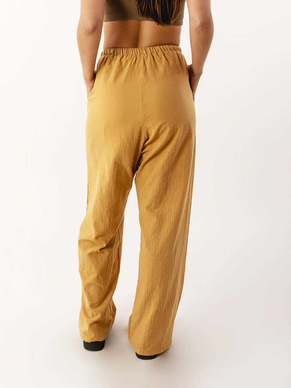 Calça Nat da Greenish em caqui, vista traseira com cós elástico e caimento solto, ideal para conforto e praticidade.