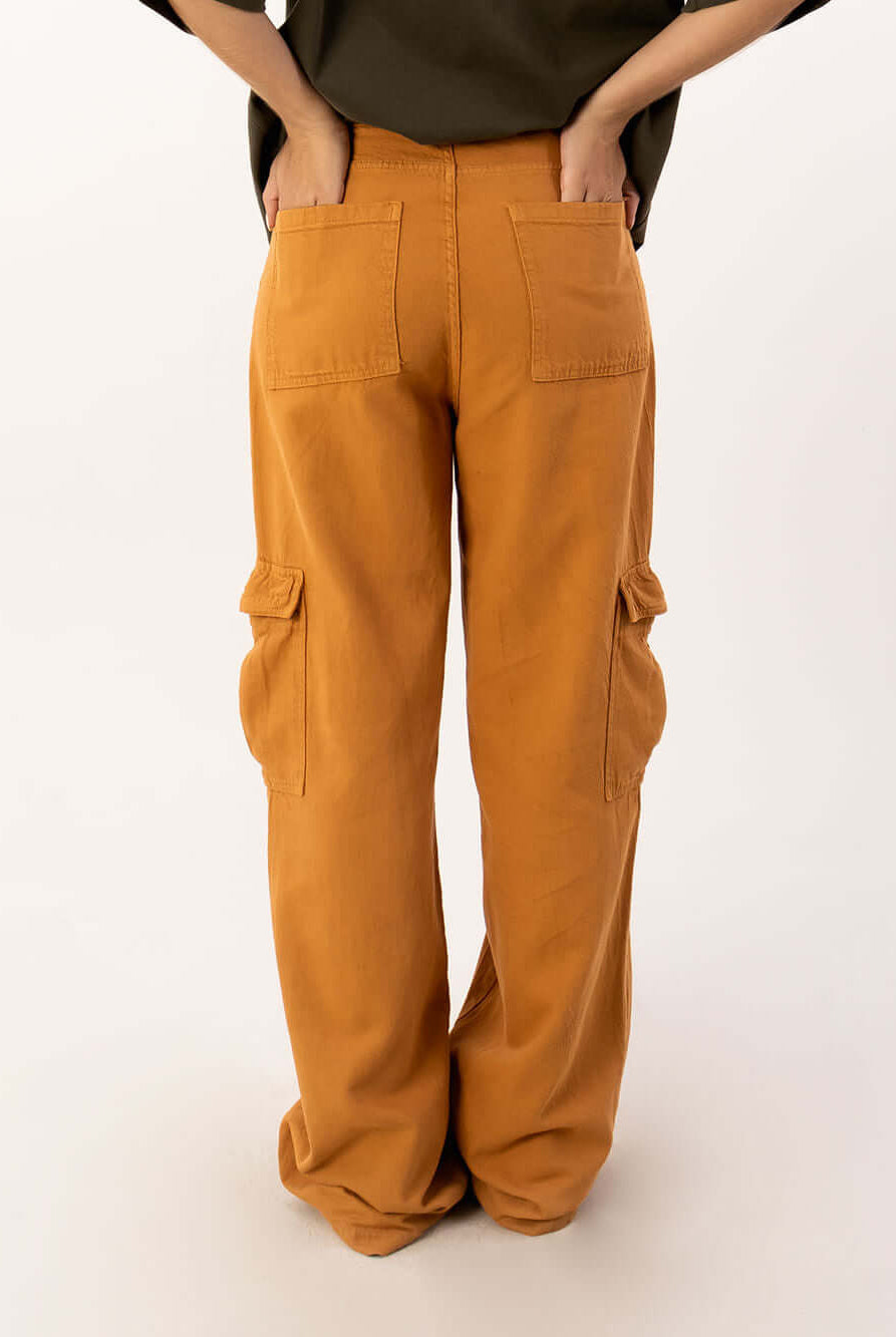 Calça cargo Lilly da Greenish na cor ocre, mostrando bolso traseiro e laterais em look moderno e prático.