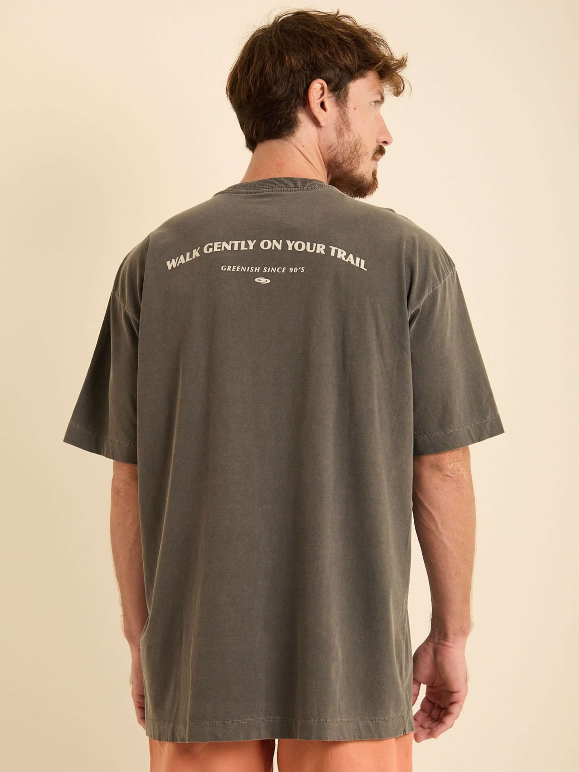 Camiseta oversized Greenish na cor chumbo, com estampa 'WALK GENTLY ON YOUR TRAIL' nas costas.