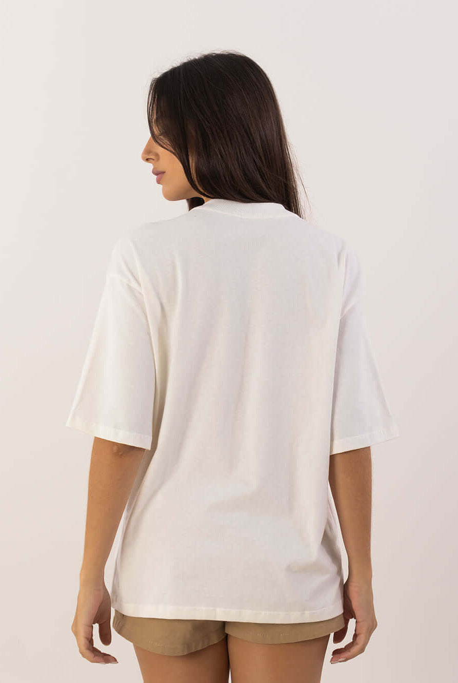 Modelo usando camiseta oversized bege da Greenish, vista de costas, mostrando o design confortável e despojado.