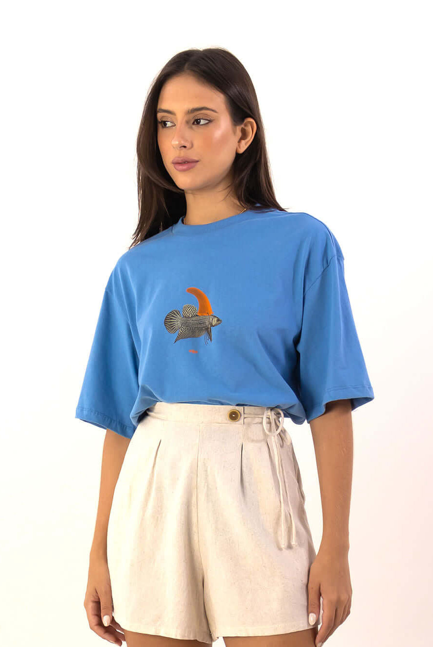 Model usando T-shirt Oversized Warning Azul da Greenish, com estampa exclusiva de peixe e short claro.
