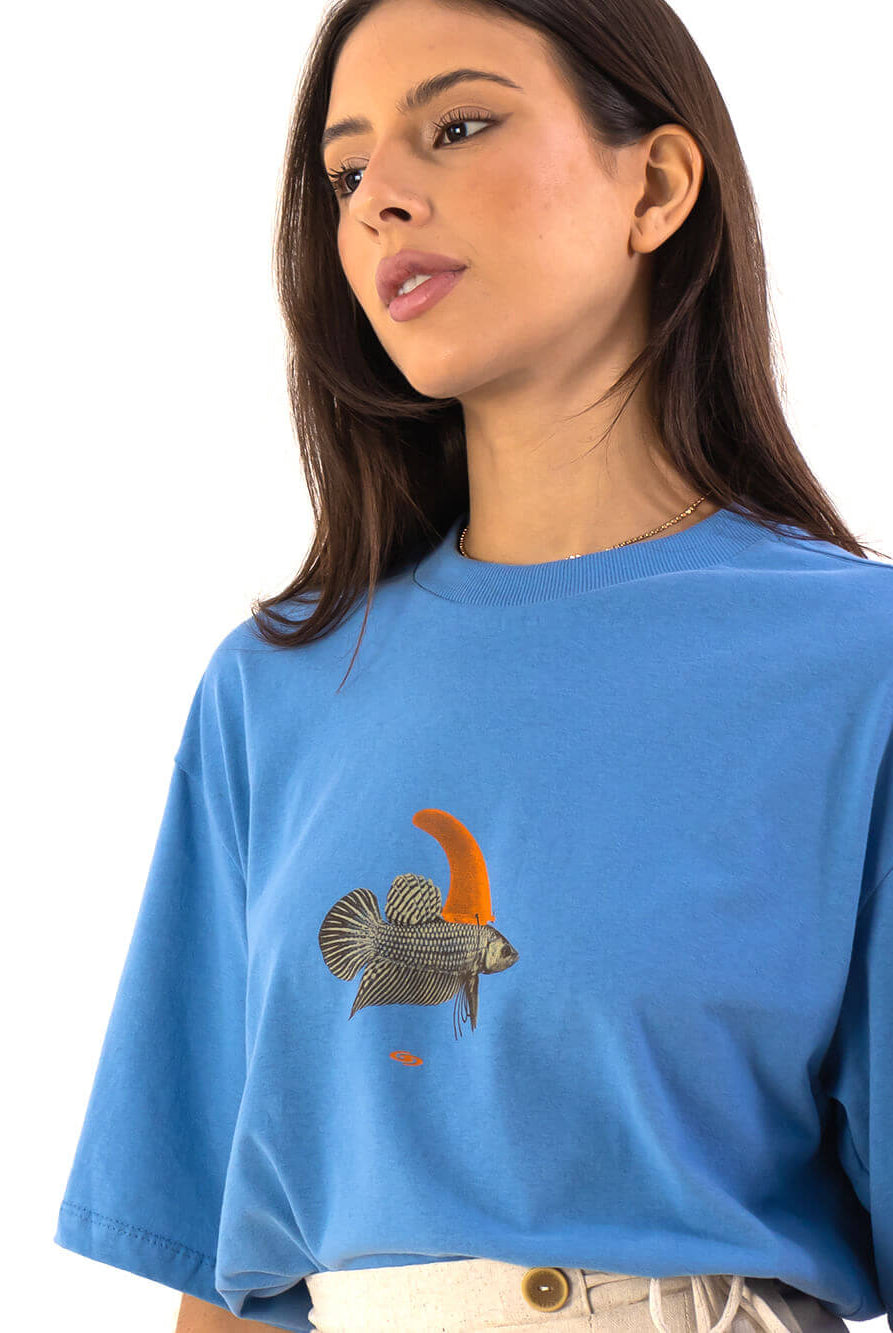 Modelo vestindo T-shirt Oversized Warning Azul da Greenish, com estampa de peixe e gola larga.