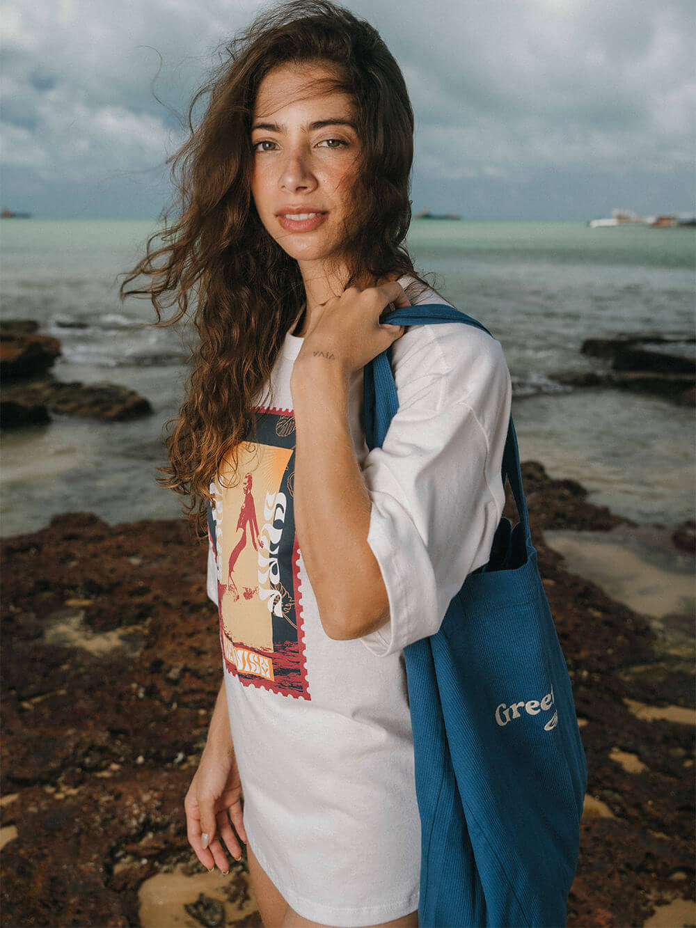Modelo usando camiseta oversized Soul Surf Girl da Greenish, na praia, transmitindo estilo e conforto.