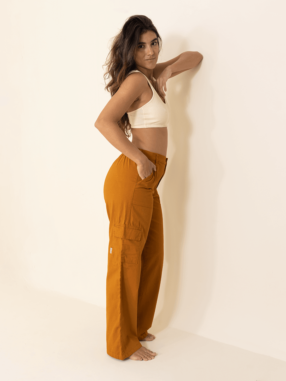 Calça cargo sarja caramelo da Greenish em modelo feminino, destacando o caimento reto e prático dos bolsos laterais.