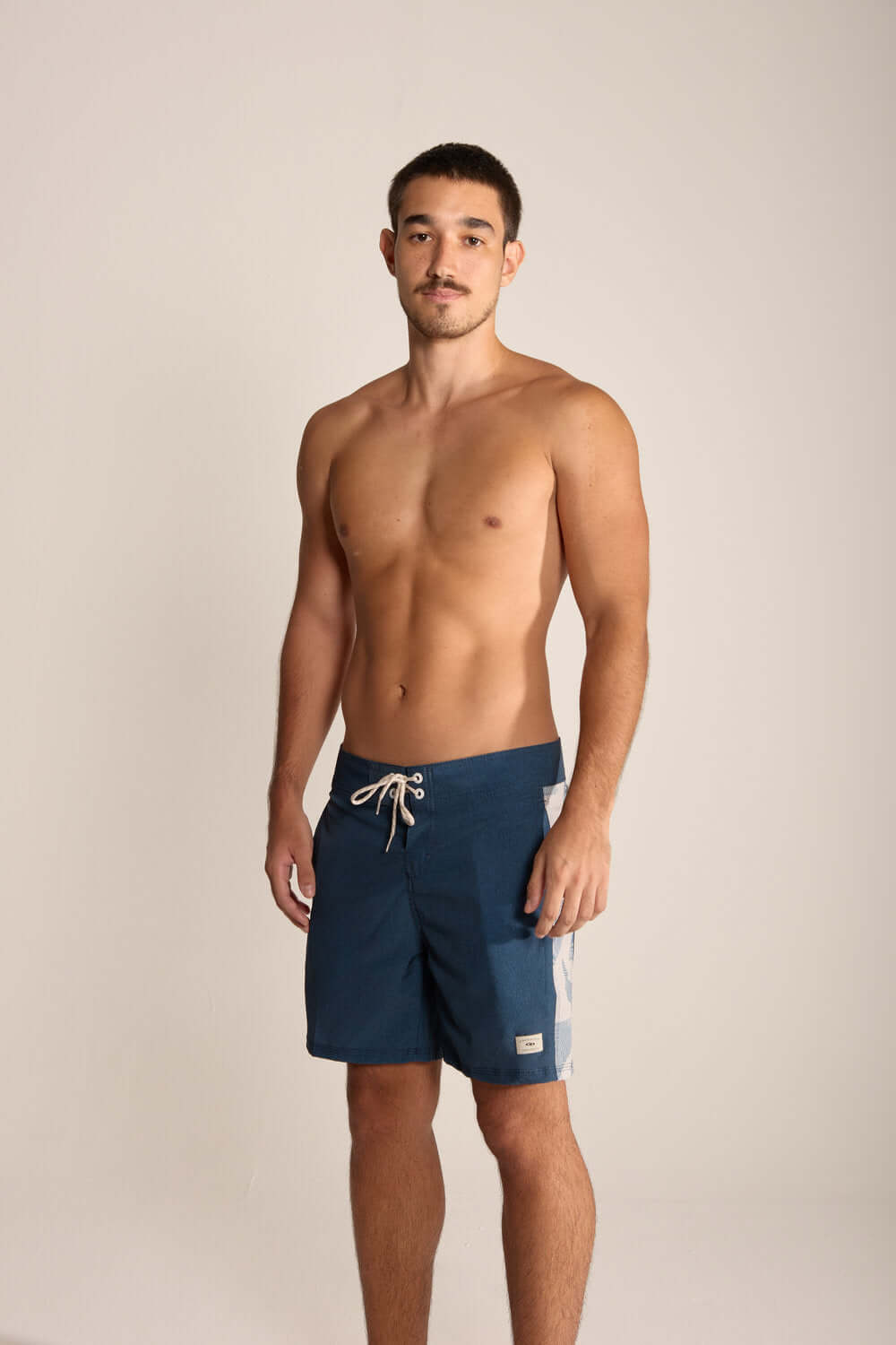 Homem usando bermuda azul marinho Boardwalk Live the Simple, ideal para praia e esportes aquáticos.