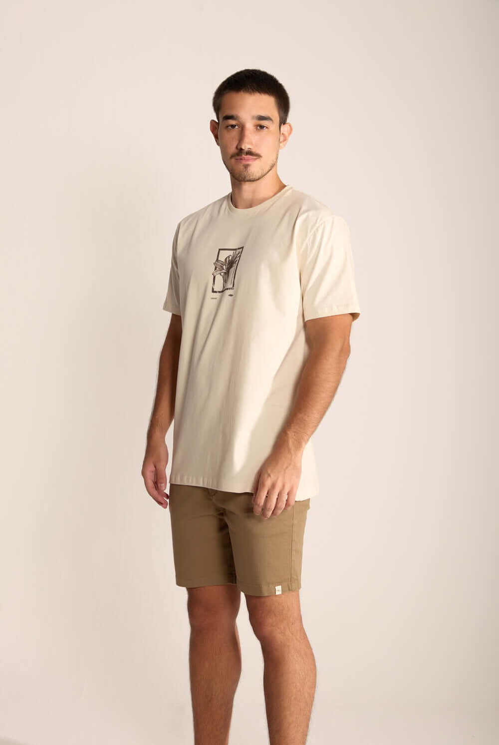 Modelo masculino usando camiseta clara e bermuda caqui, destacando estilo e conforto casual.