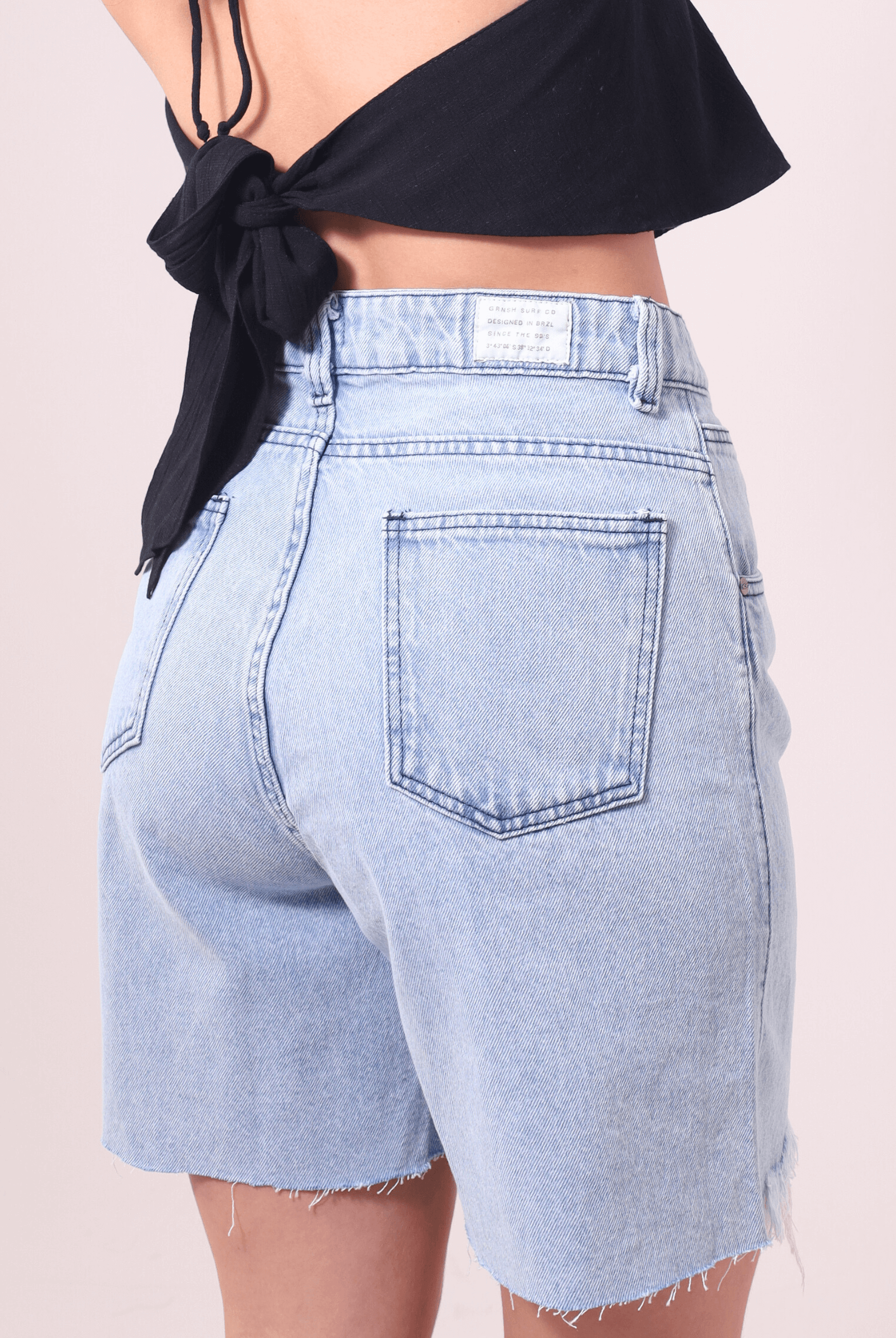 Bermuda Jeans Glicia da Greenish com cintura alta e caimento solto, lavagem azul vintage e acabamento desfiado. Moda verão atemporal.